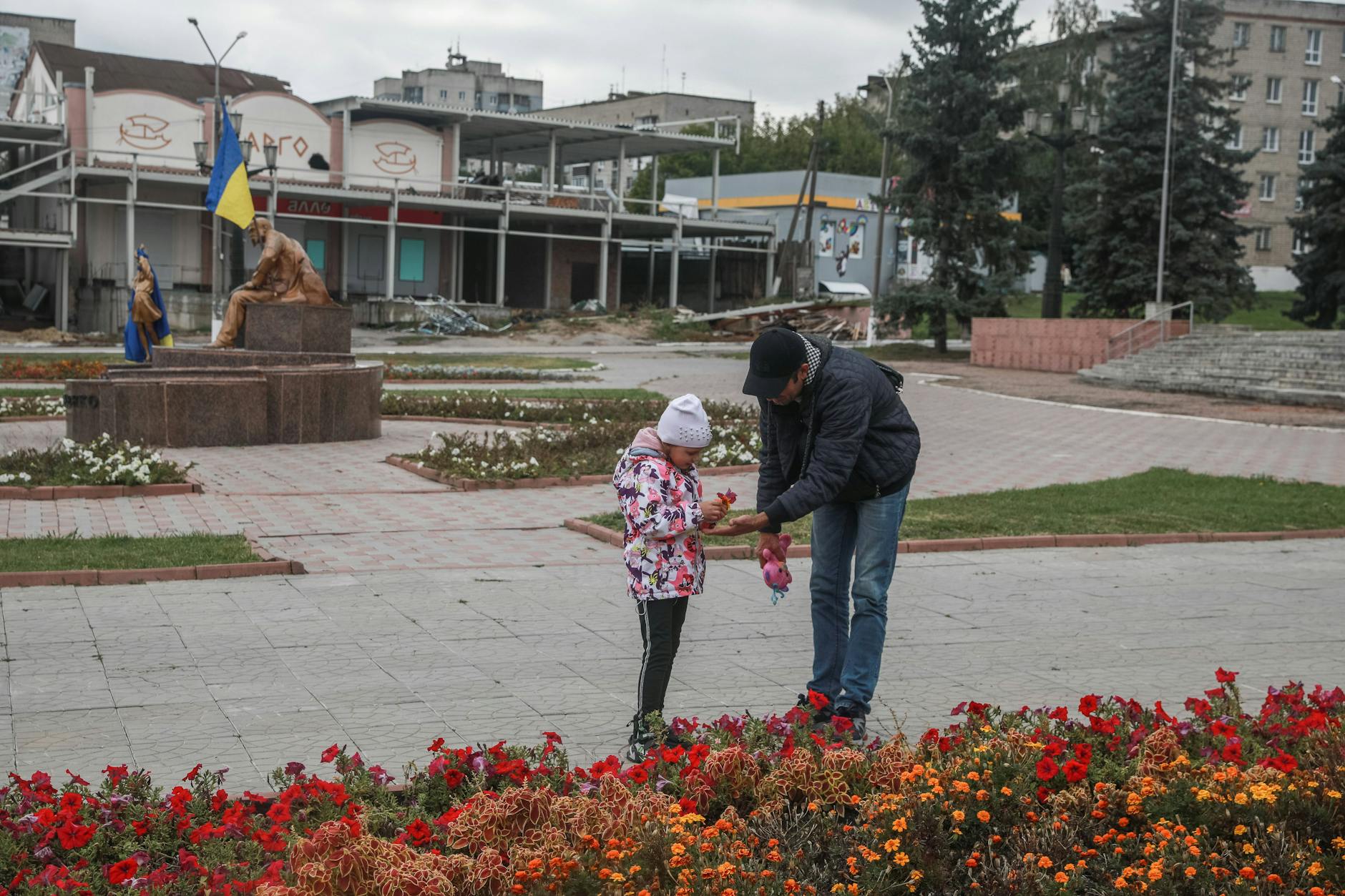 In der von den russischen Soldaten befreiten Stadt Balakliya, Region Charkiw. Vater und Tocher sammeln Blumen.
