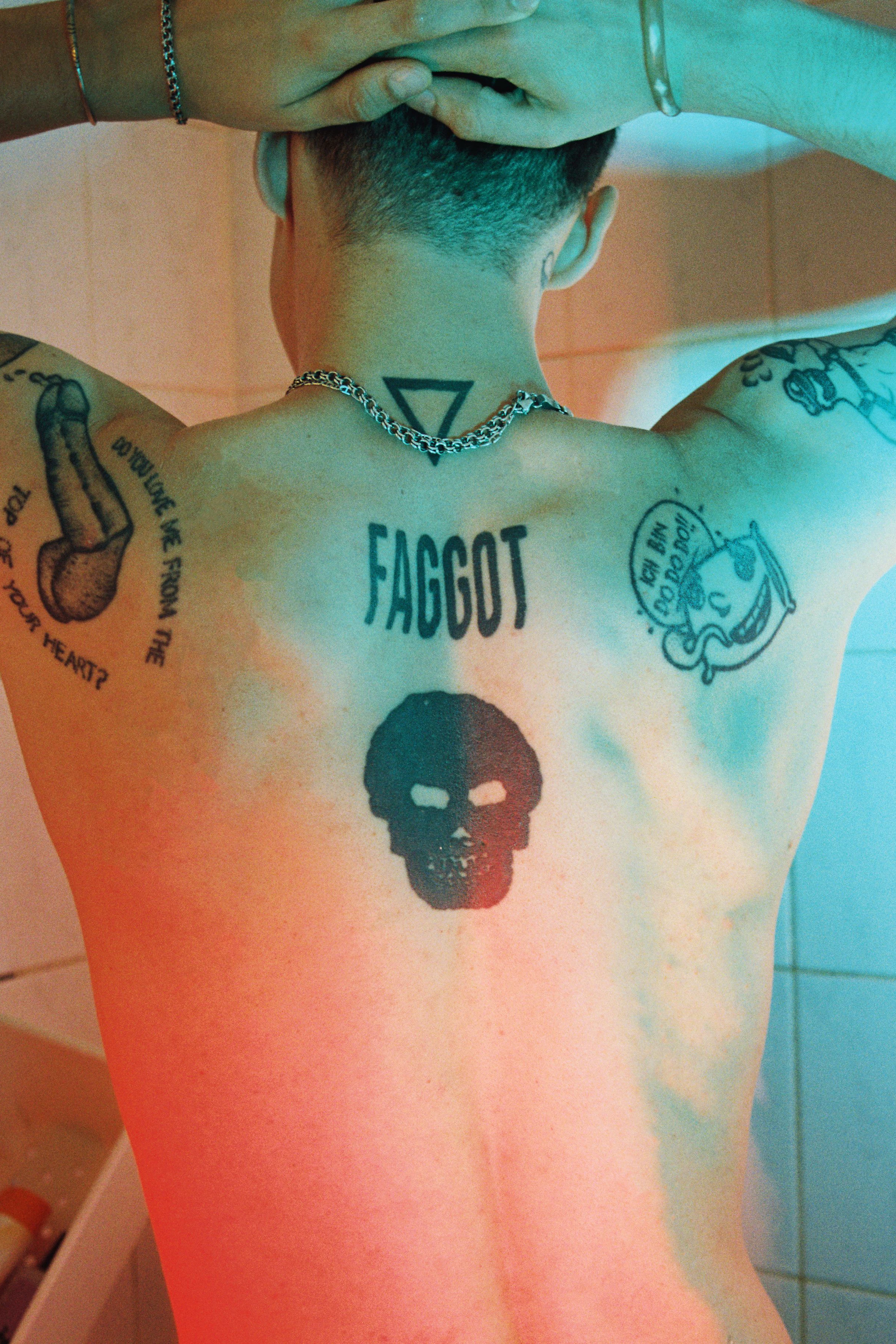 „Faggot“ ist auf seinen Rücken tätowiert, zu deutsch: Schwuchtel