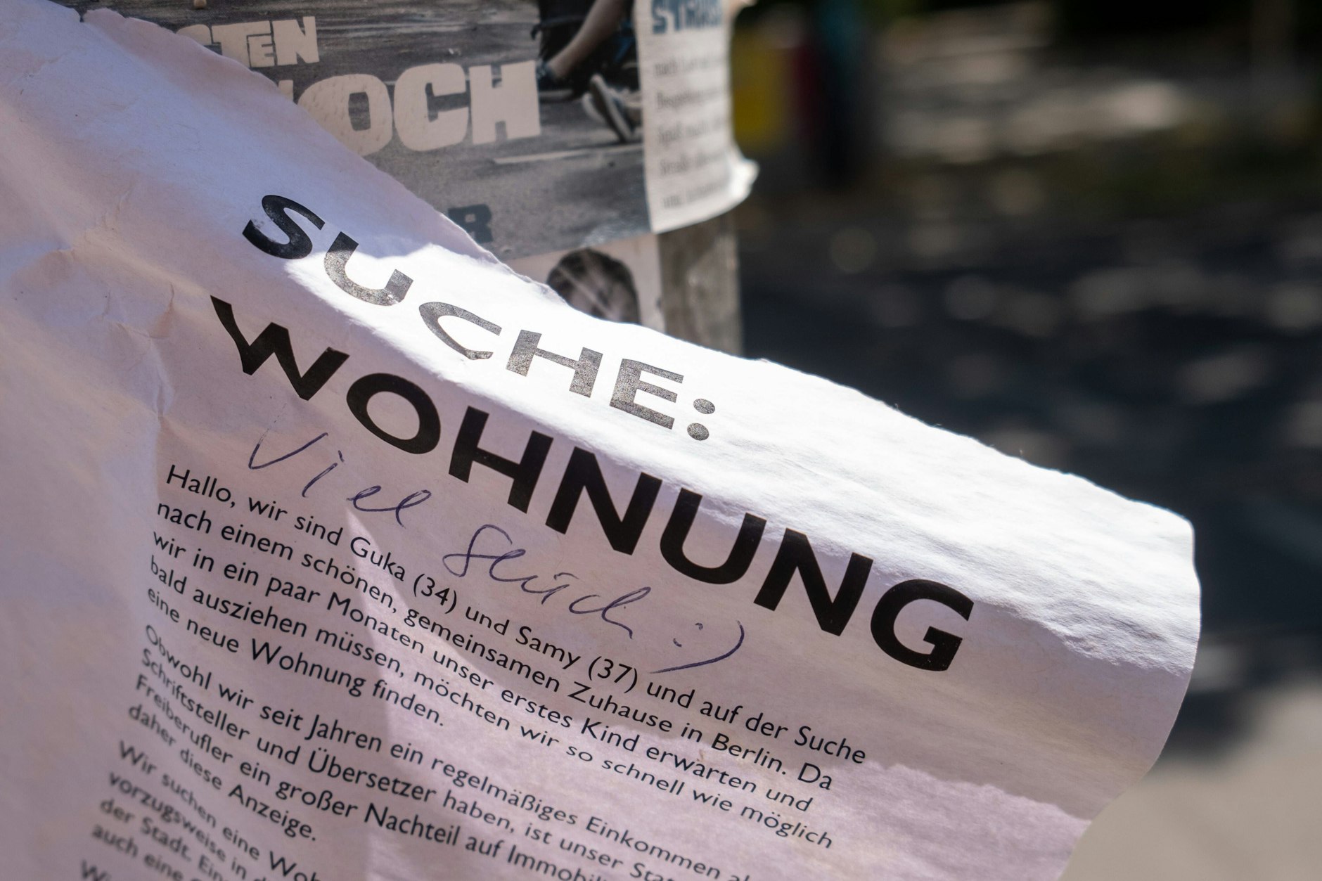 Ein mit den Worten Viel Glück kommentiertes Wohnungsgesuch an einem Berliner Laternenmast.