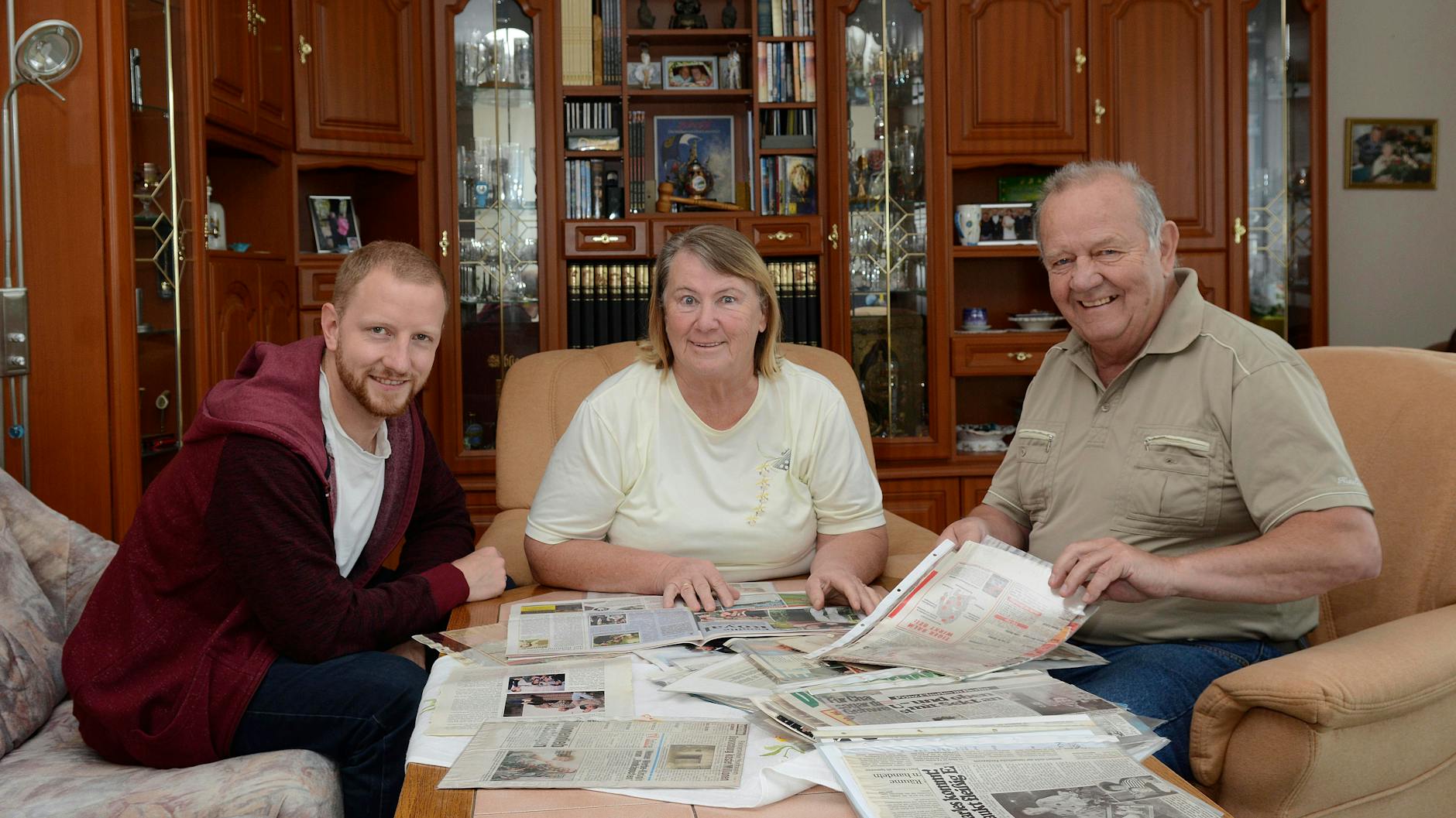 Familie Kunze in ihrem neuen Domizil: Eva -Maria und ihr Mann Herbert sehen sich mit Sohn Christian die alten Zeitungsberichte an, als Prinz Charles in Hellersdorf ihr Gast war.