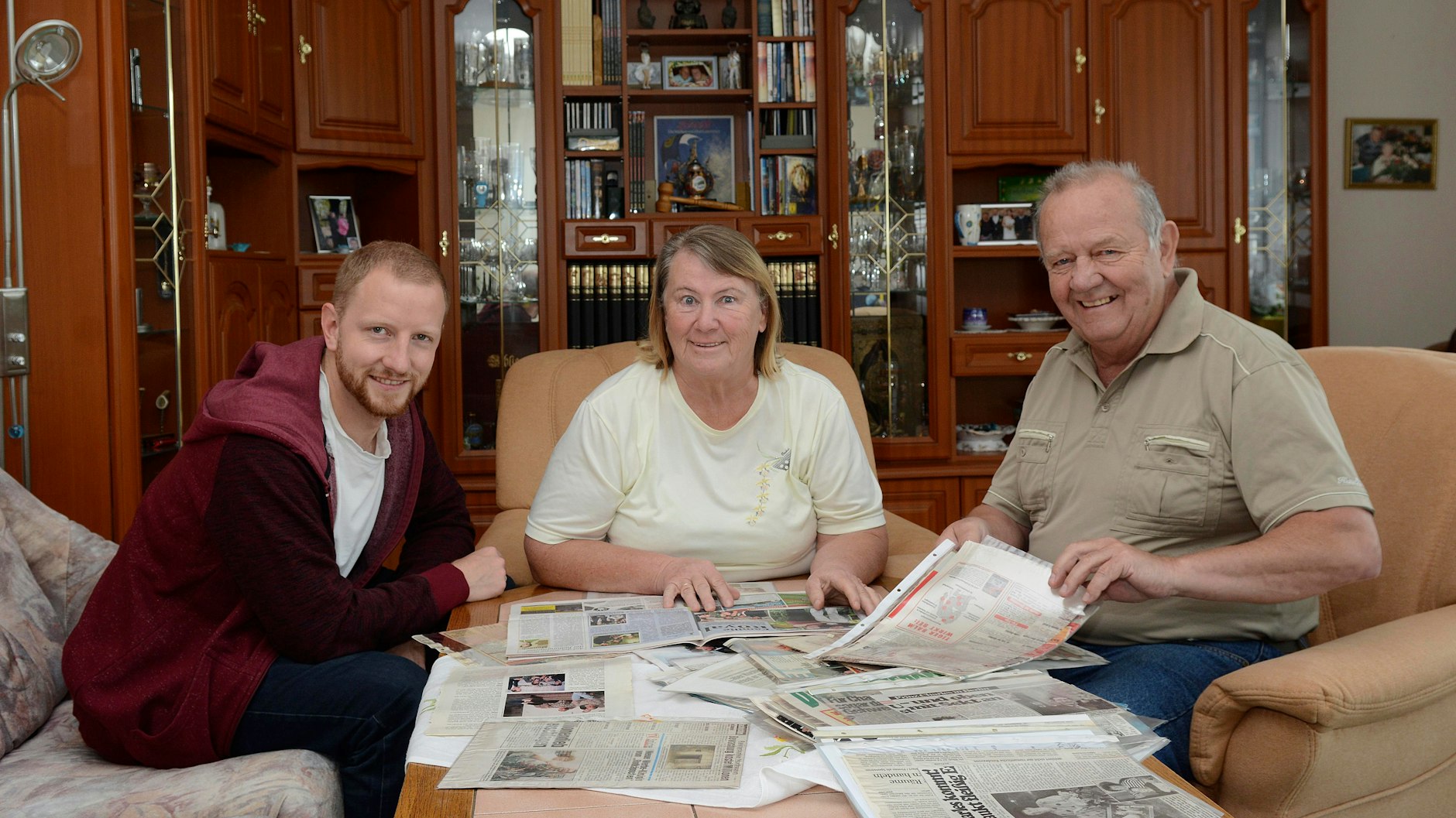 Familie Kunze in ihrem neuen Domizil: Eva -Maria und ihr Mann Herbert sehen sich mit Sohn Christian die alten Zeitungsberichte an, als Prinz Charles in Hellersdorf ihr Gast war.