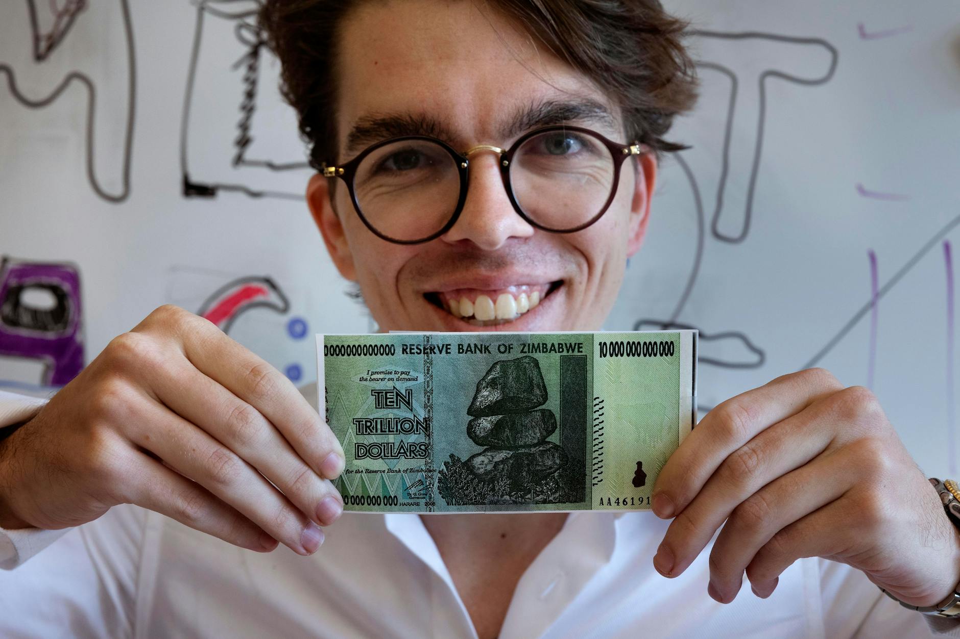 Eric Martinez, Doktorand in der Abteilung für Gehirn- und Kognitionswissenschaften am Massachusetts Institute of Technology, hält einen simbabwischen 10-Billionen-Dollar-Schein in der Hand. Martinez, der auch ein Jurastudium an der Harvard University absolviert hat, teilte sich den Ig-Nobelpreis für Literatur mit Francis Mollica und Edward Gibson für die Analyse der Ursachen, die das Verständnis von Rechtsdokumenten unnötig erschweren. 
