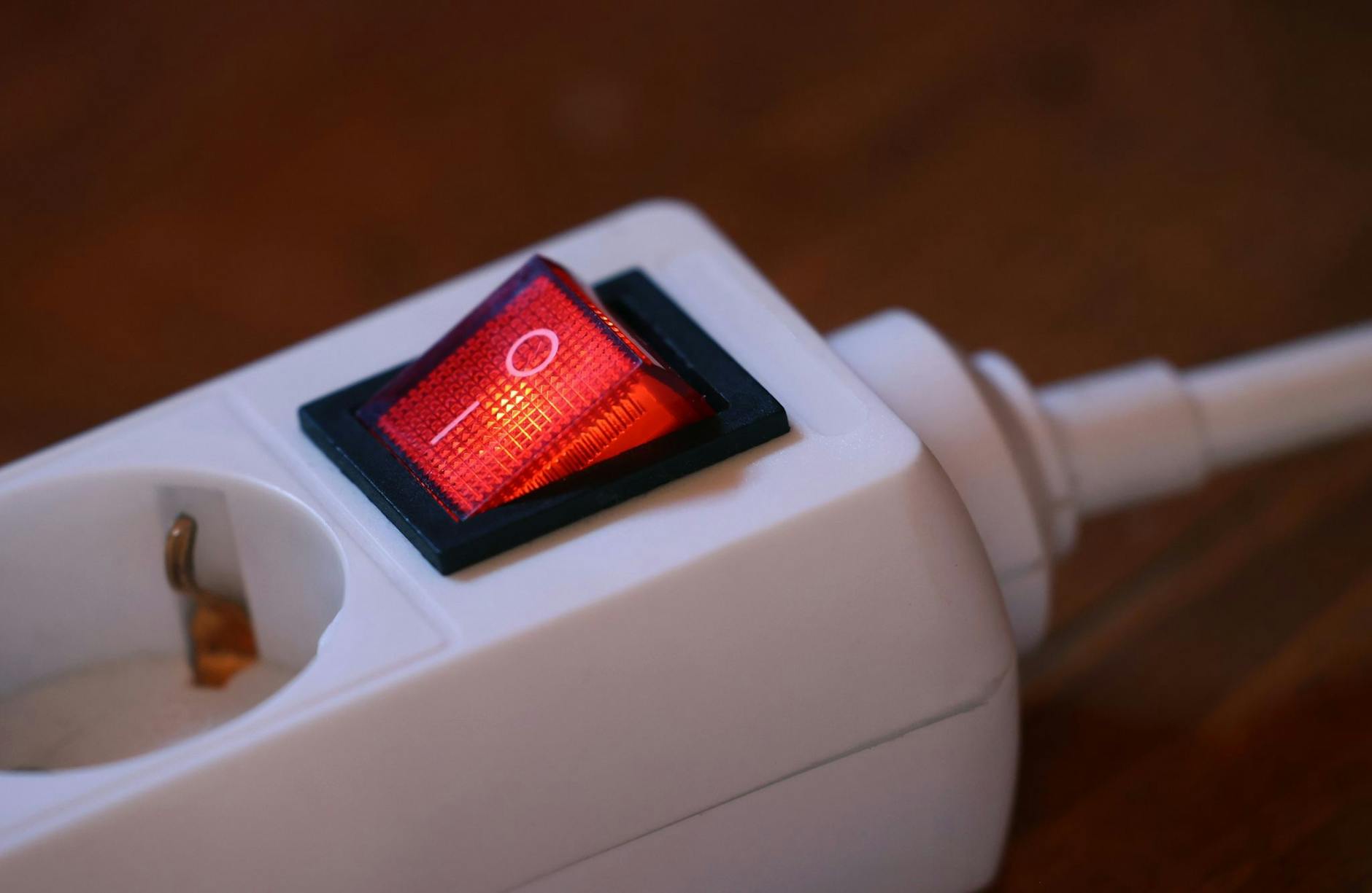 Der eingeschaltete Schutzschalter einer Mehrfachsteckdose leuchtet rot. lbild