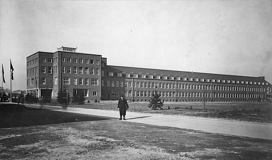 Das Verwaltungsgebäude der Henschel Flugzeug-Werke in Schönefeld, errichtet 1935 als architektonisches Symbol der modernen Zeit unter der Maxime: dauerhaft, sparsam, funktional. Im Vordergrund Werksdirektor Walter Hormel. Heute nutzt die BER-Verwaltung das Gebäude, im Kopfbau links residiert die Geschäftsführung.