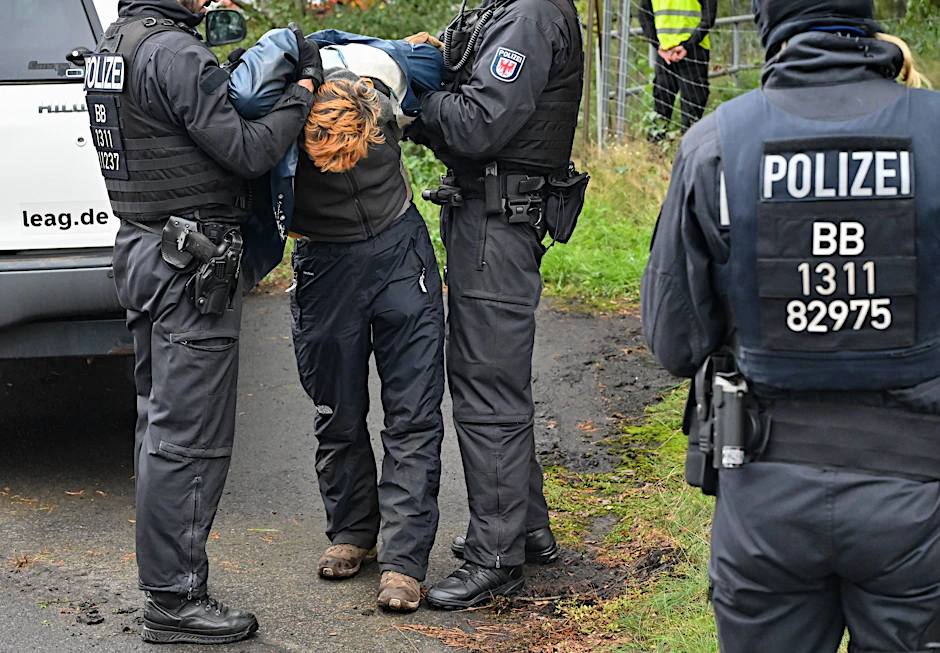 Ein Klimaaktivist wird von der Polizei abgeführt, nachdem er eine Gleisverbindung für den Transport von Braunkohle zum Kraftwerk Jänschwalde blockiert hatte.