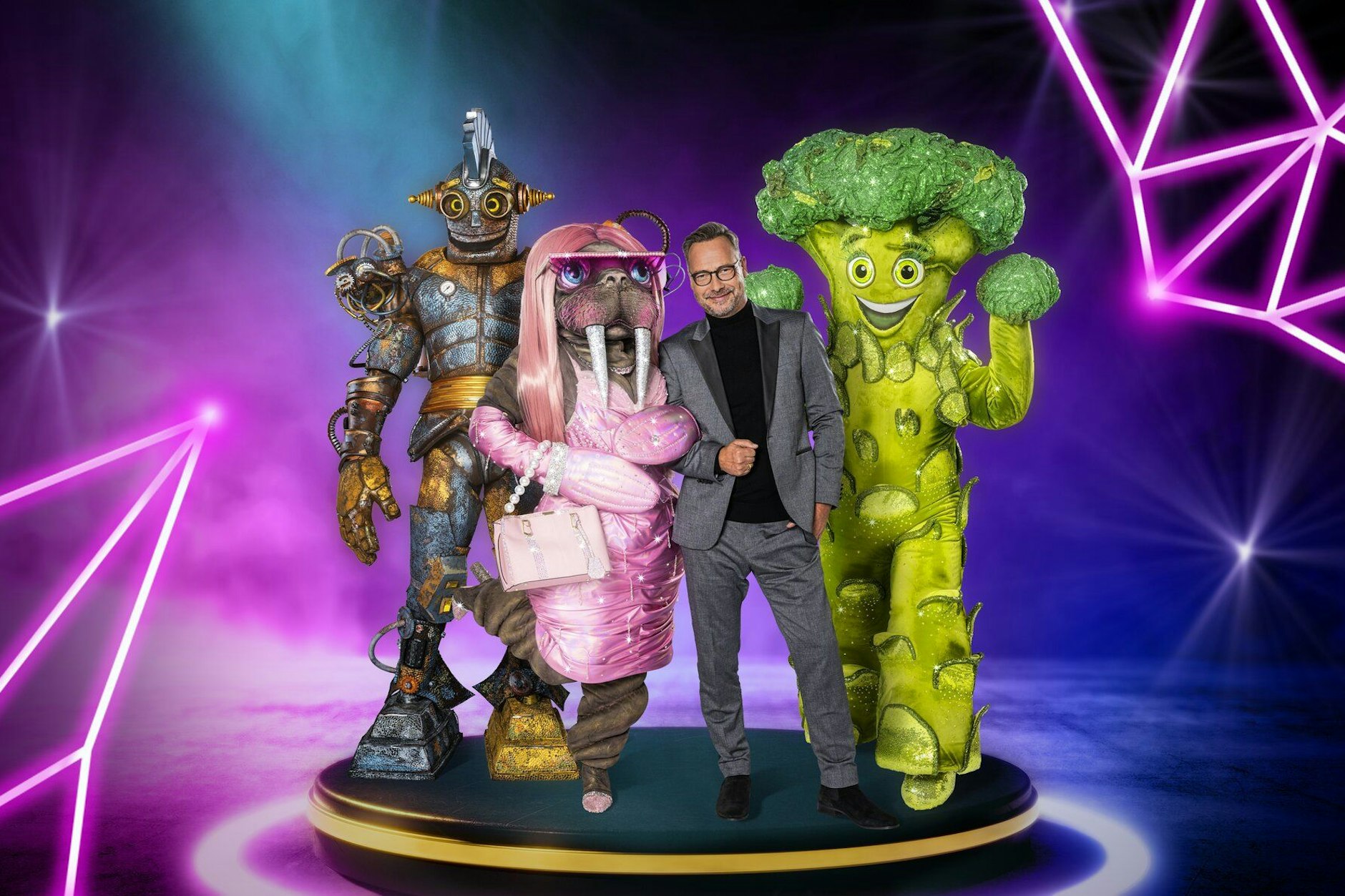 Moderator Matthias Opdenhövel mit den ersten drei Kostümen der neuen Staffel von The Masked Singer.