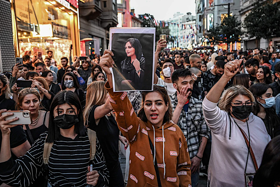Demonstranten in der iranischen Hauptstadt Teheran. Eine Frau hält ein Porträt der toten Mahsa Amini in die Höhe.