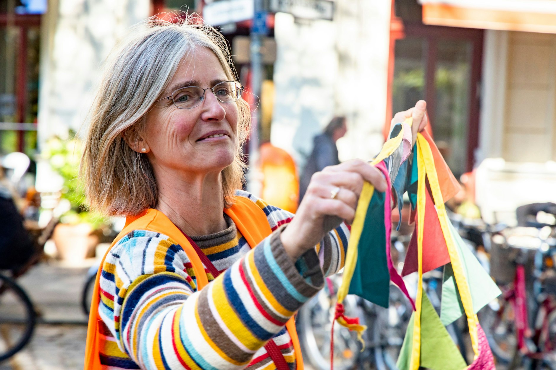 Cornelia Dittrich spannt einen Seil mit bunten Fähnchen, um die autofreie Straße in Kreuzberg zu markieren.&nbsp;