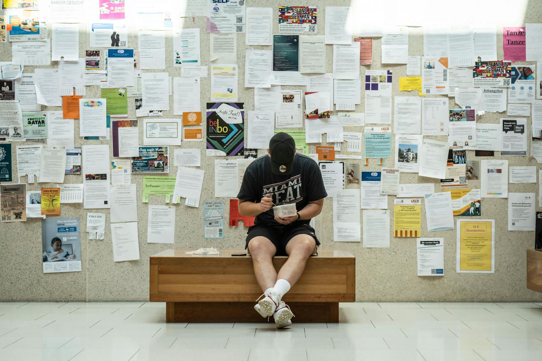 Ein Studierender sitzt vor einer Wand mit vielerlei Anzeigen.