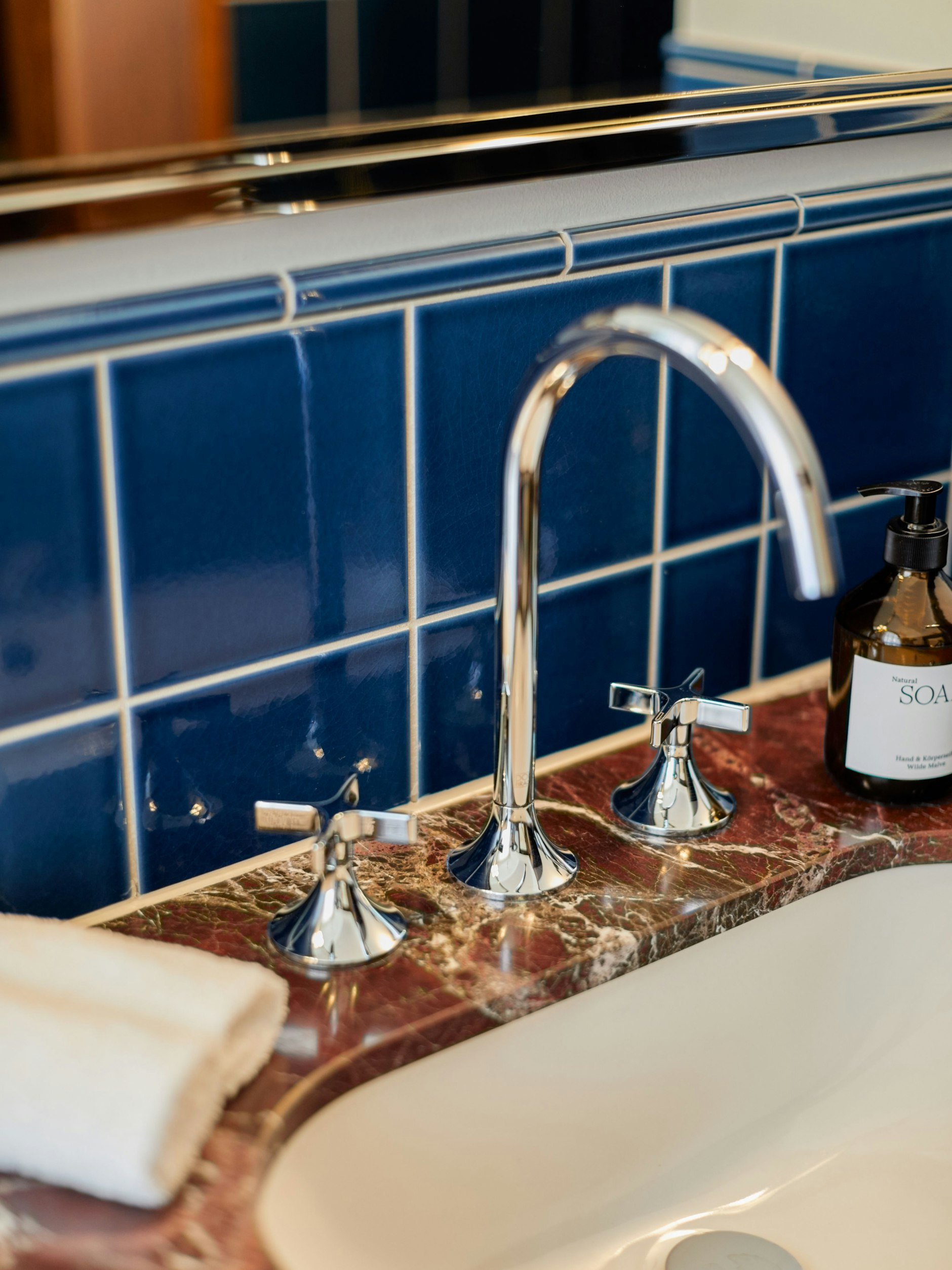 Materialschlacht: Blaue Craquelé-Fliesen kontrastieren mit rotem Marmor.