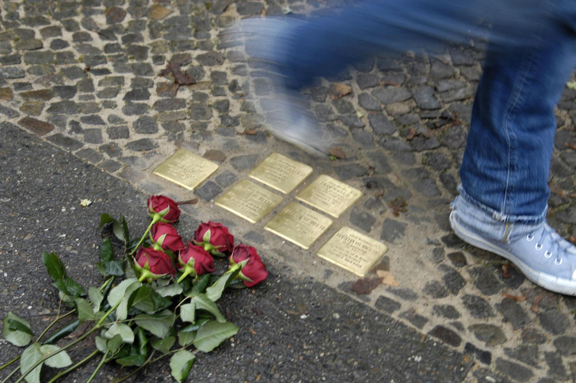 Eine Passantin geht an sechs in den Boden eingelassenen Stolpersteinen zur Erinnerung an die Opfer des Nationalsozialismus vorbei. 