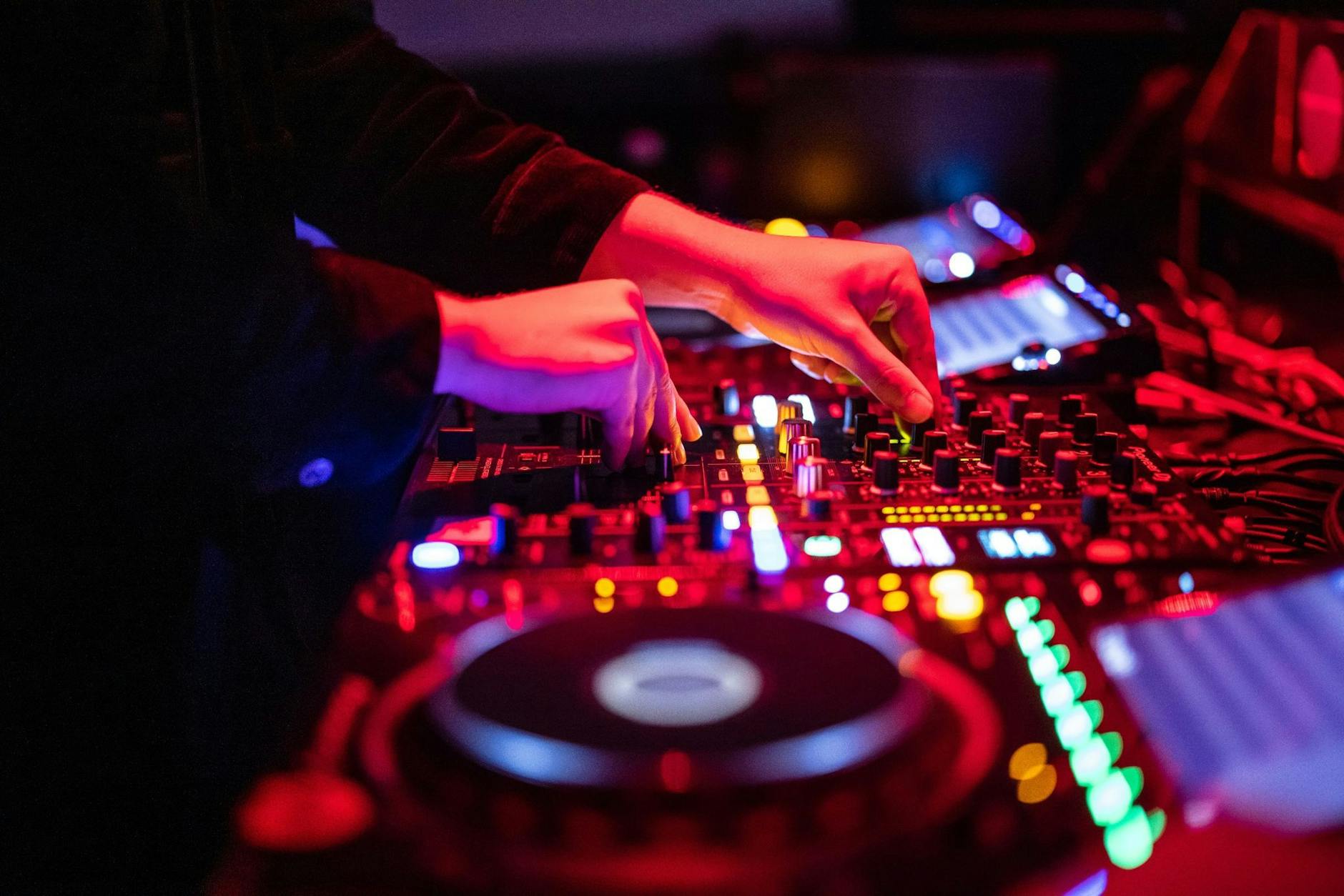 Ein DJ steht in einem Club am Mischpult.
