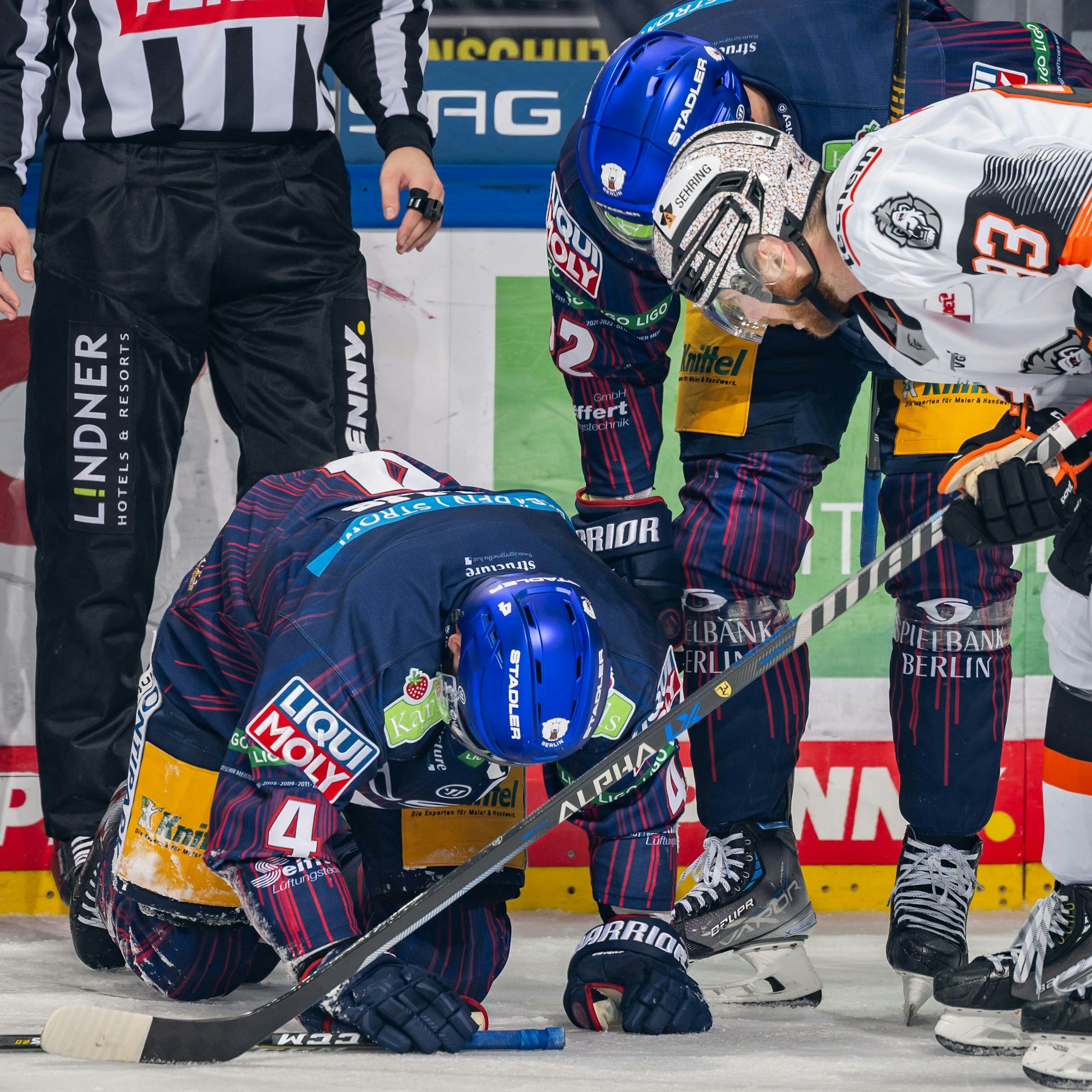 Eisbären-Vize-Kapitän Morgan Ellis kniet nach dem Pucktreffer im Gesicht auf dem Eis.