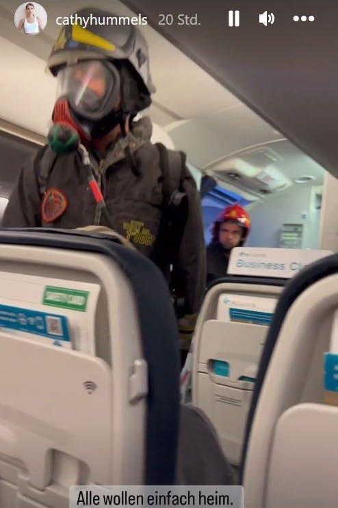 Feuerwehrmänner mit Atemmasken laufen durch das Flugzeug.