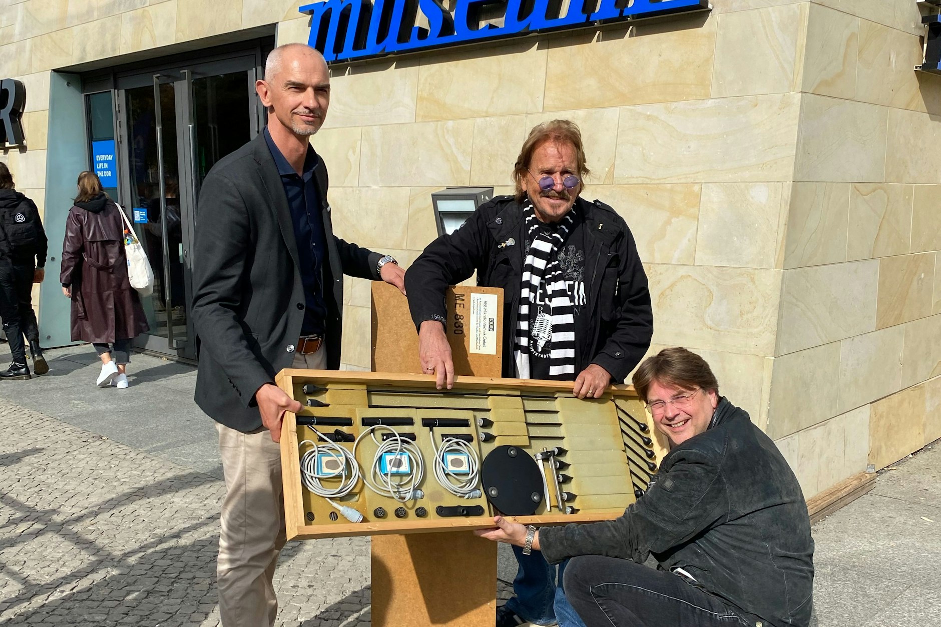 Entertainer Frank Zander (Mitte) überreicht den Mitarbeitern des DDR-Museums die volkseigenen Mikrofone.