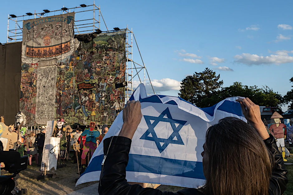 Eine Frau mit einer Israel-Flagge steht vor dem teilweise verhüllten Banner des Kollektivs Taring Padi auf der Documenta 15.