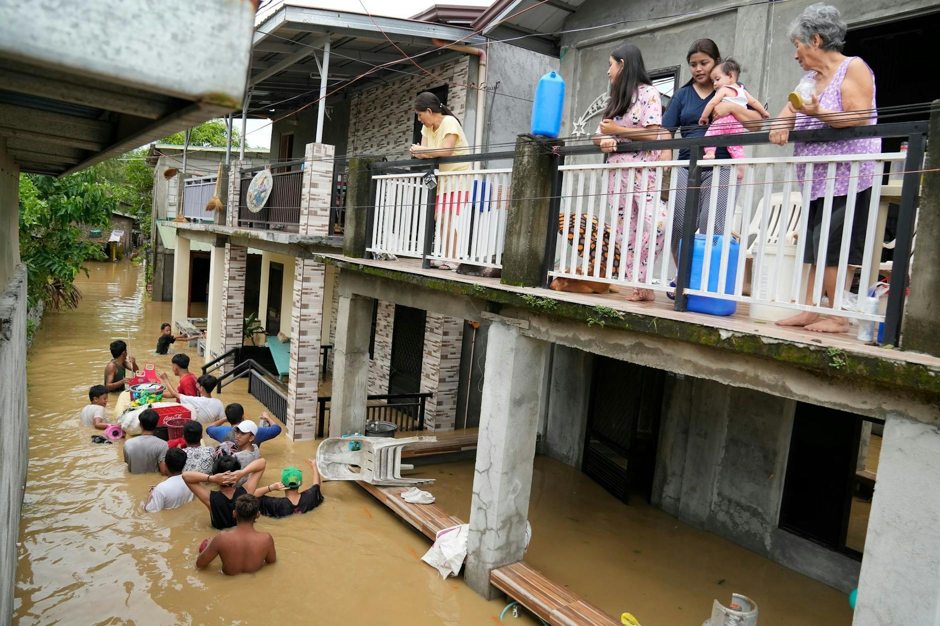 dpatopbilder - Anwohner stehen auf der Terrasse ihres Hauses in San Miguel in der philippinischen Provinz Bulacan, während andere eine durch den Taifun «Noru» überschwemmte Straße passieren. Der Taifun verursachte schwere Schäden; mindestens fünf Menschen kamen ums Leben.