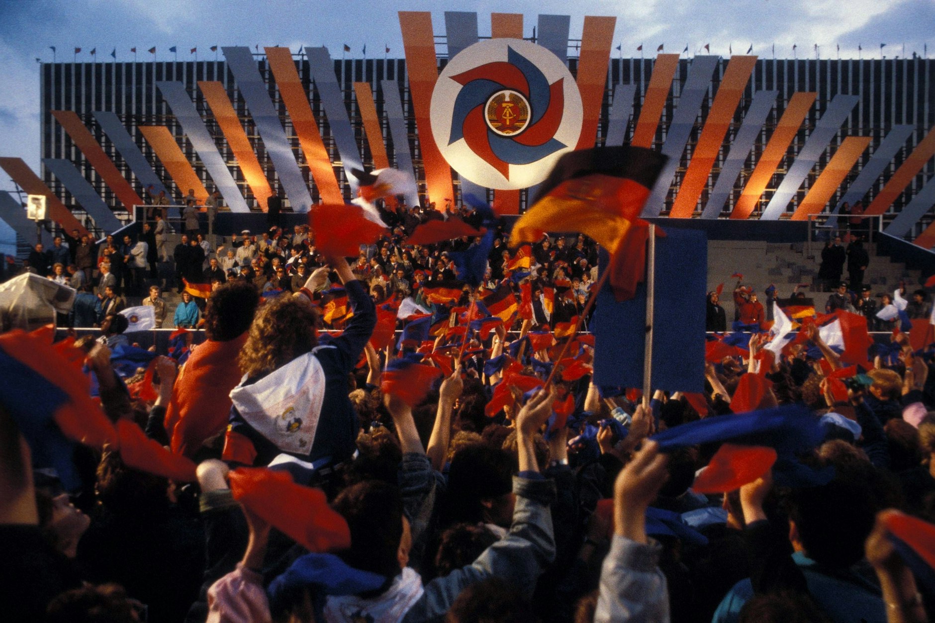 Winkende Jugendliche vor der Ehrentribüne: Pfingsttreffen der FDJ 1989 in Ost-Berlin, DDR.