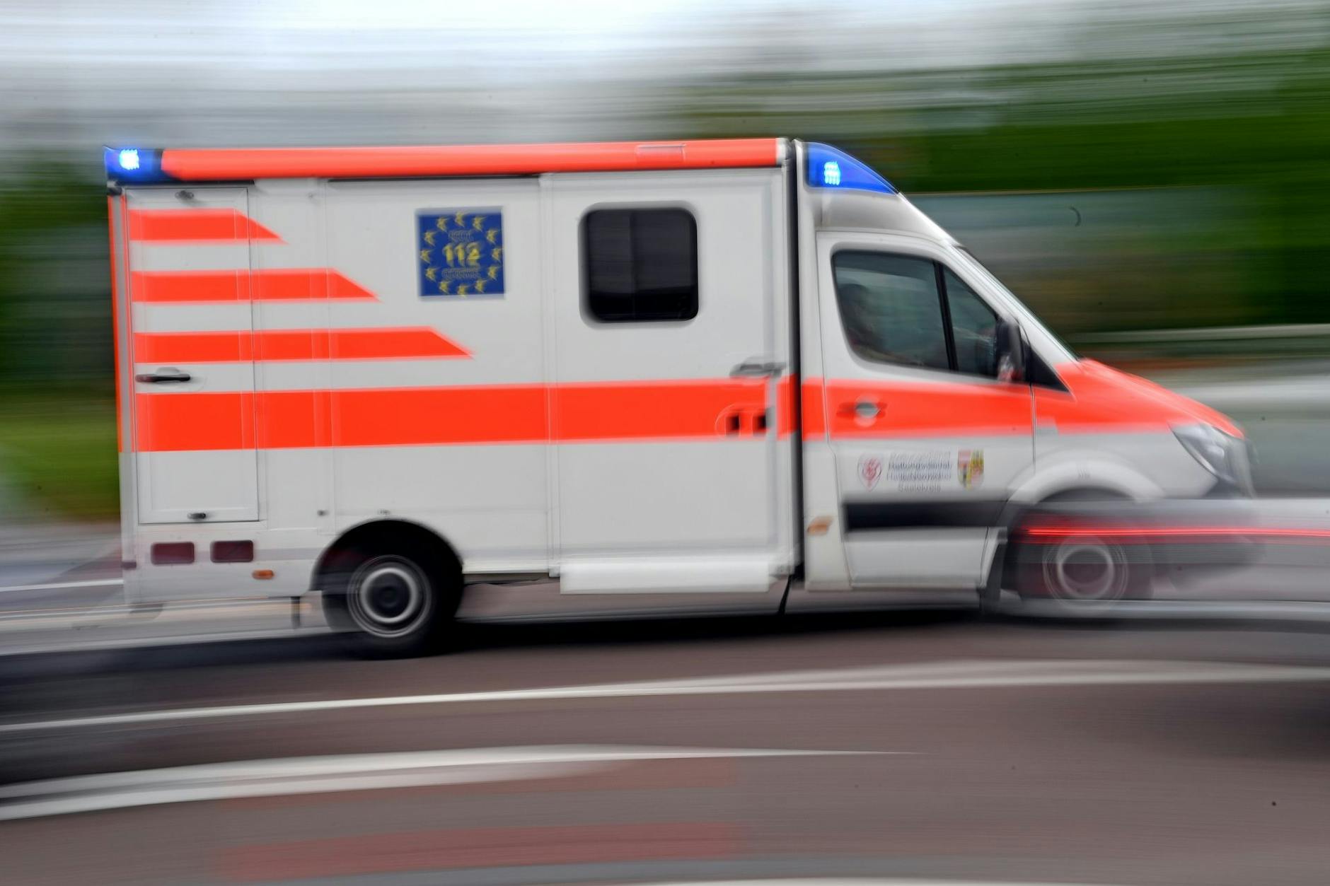 Ein Krankenwagen fährt mit Blaulicht auf einer Straße.