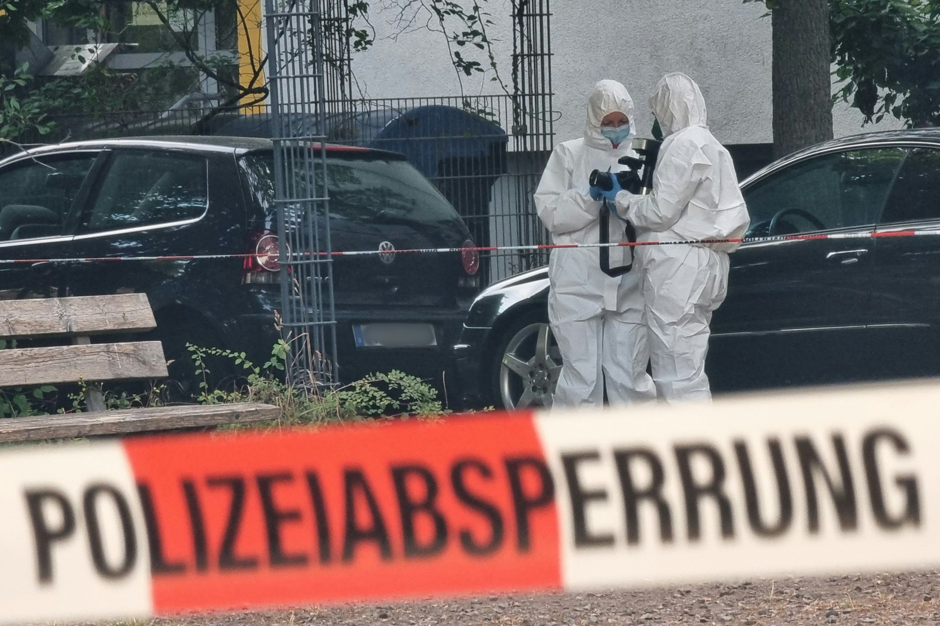 Beamte der Kriminaltechnik stehen hinter einer Polizeiabsperrung. (Symbolbild)