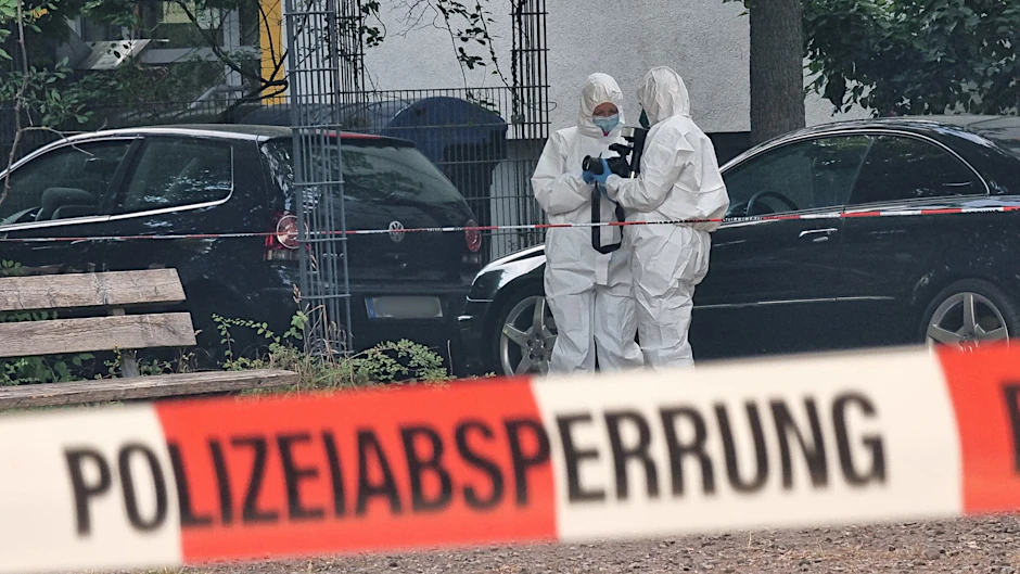 Beamte der Kriminaltechnik stehen hinter einer Polizeiabsperrung. (Symbolbild)