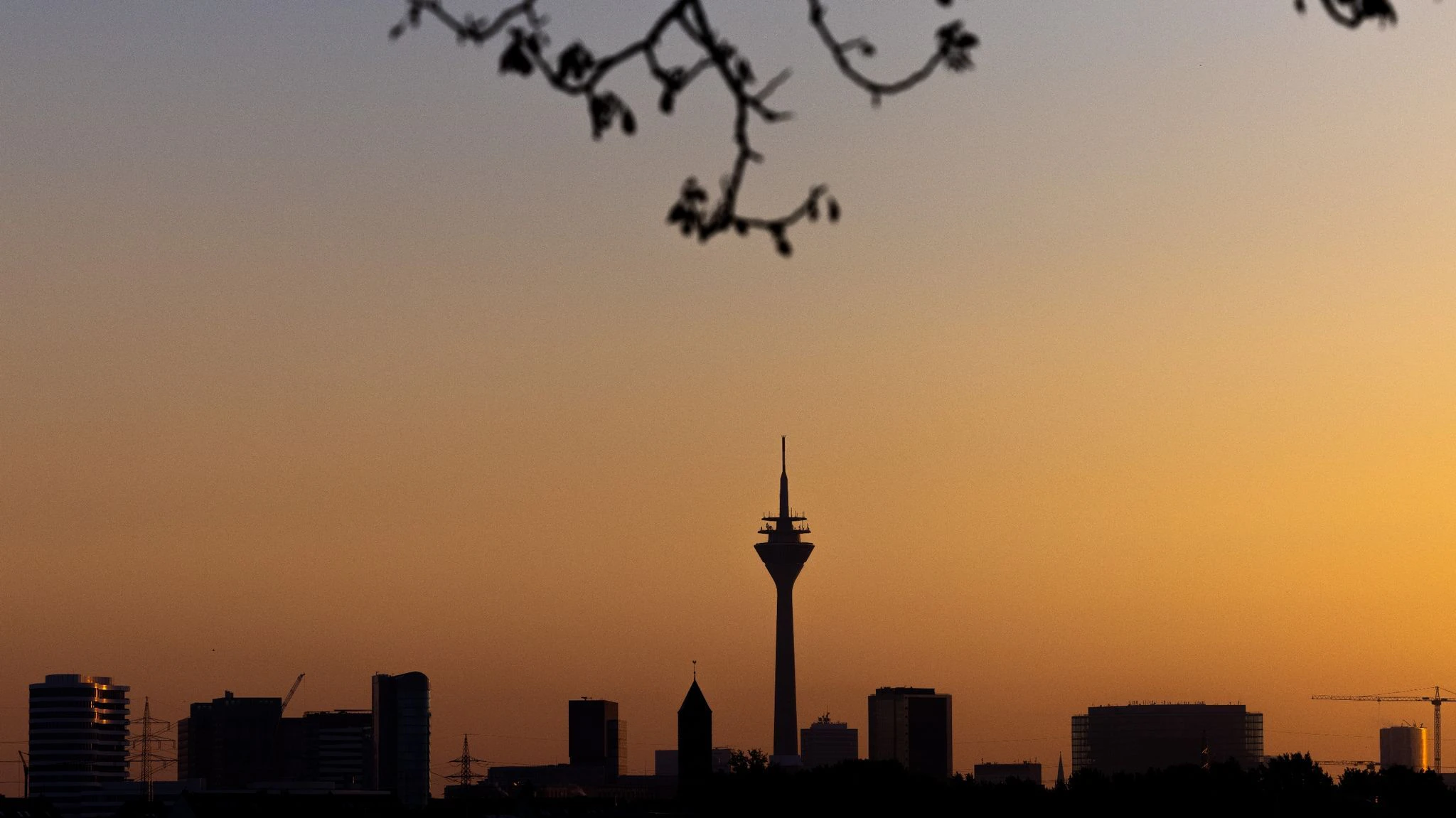 Der Blick aus Neuss am Morgen ist beeindruckend: Die Sonne geht über der Stadtsilhouette von Düsseldorf mit dem Rheinturm und dem Medienhafen auf.  