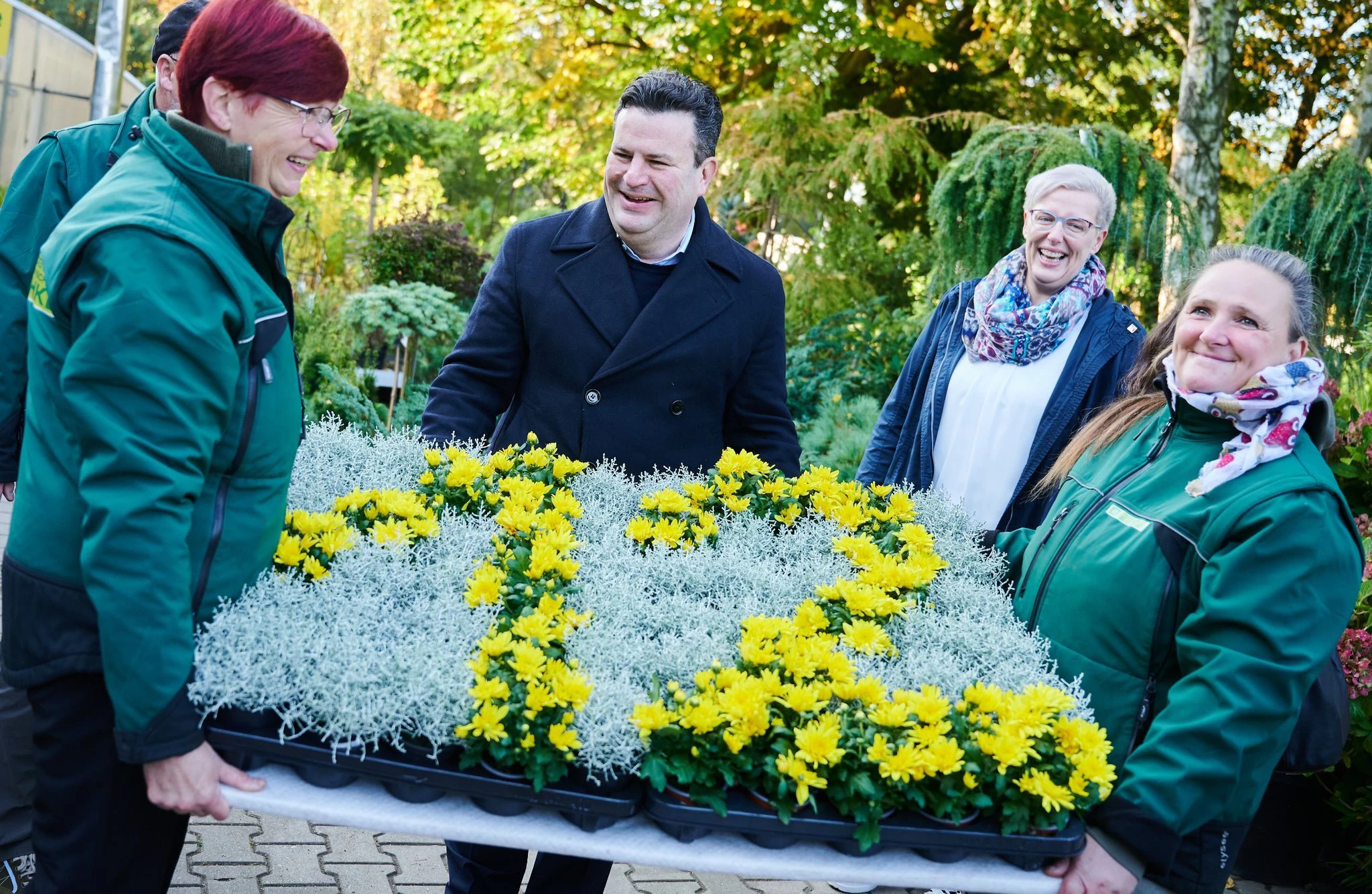 Bundesarbeitsminister Hubertus Heil (M) hilft, ein Blumengesteck zu tragen, das die Zahl Zwölf zeigt. Am 1. Oktober 2022 wird der gesetzliche Mindestlohn auf 12 Euro pro Stunde erhöht.  