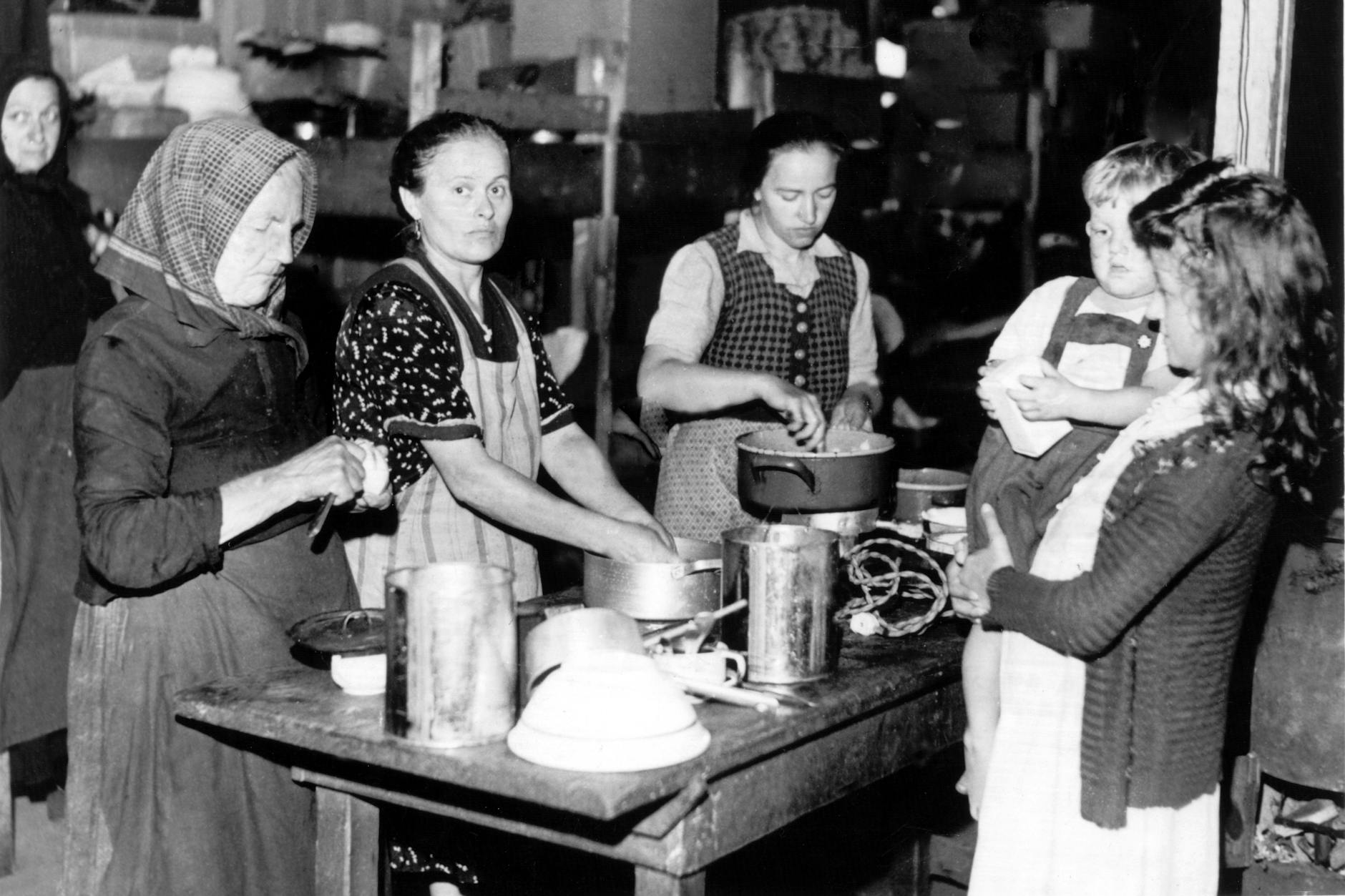 Frauen bereiten 1948 an einem Tisch Mahlzeiten zu. 