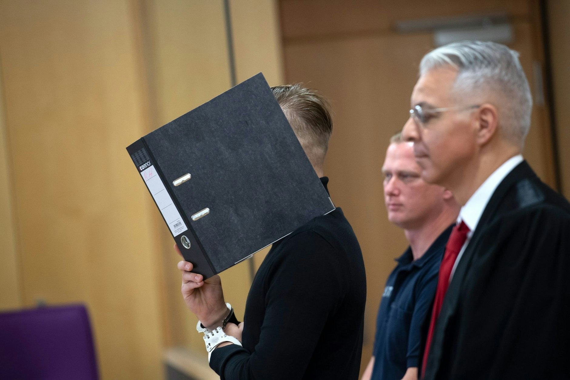 Der angeklagte Suff-Raser hält sich in einem Saal des Landgerichts Neuruppin einen Ordner vor das Gesicht.