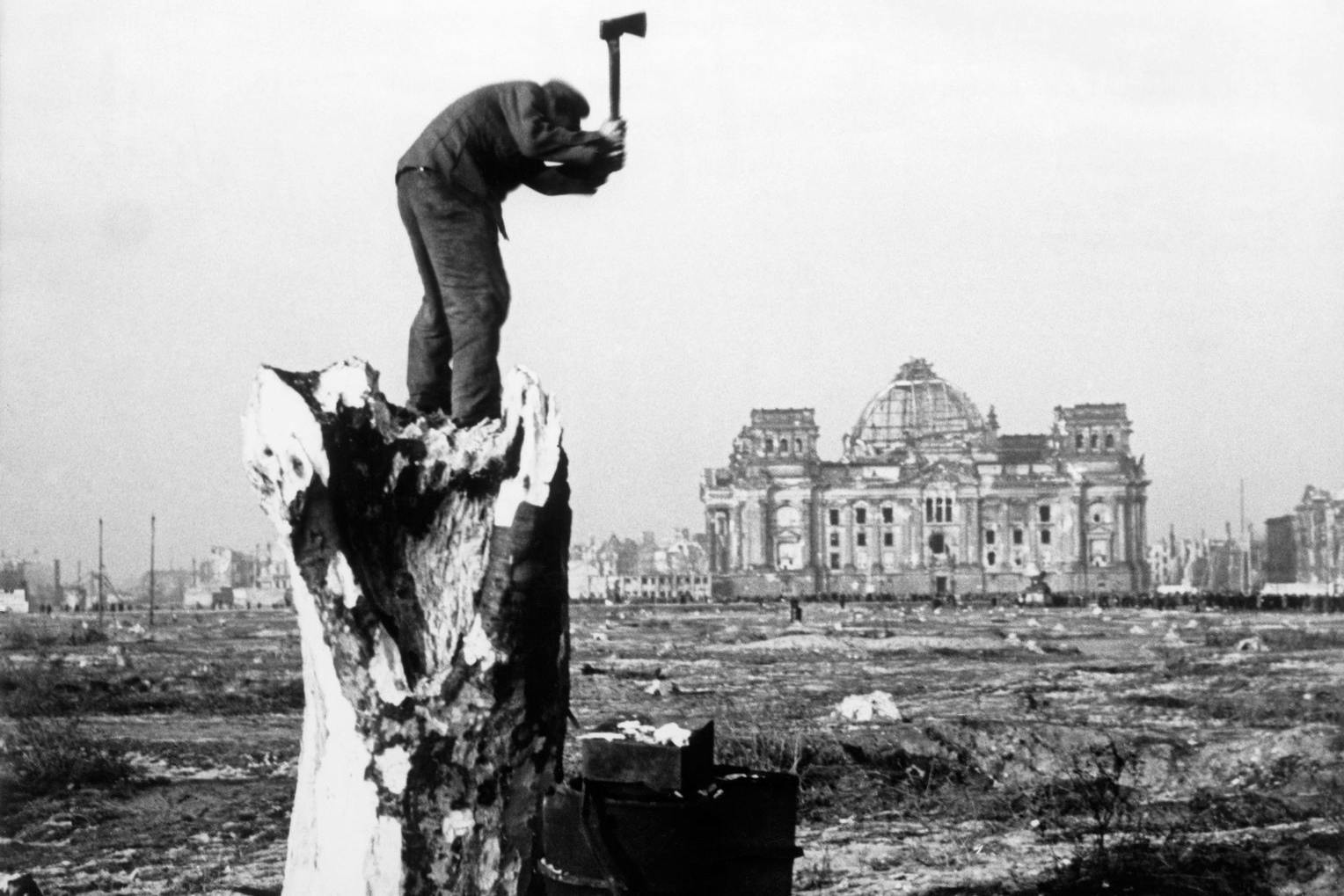 Kurz nach Kriegsende im Tiergarten, gegenüber das ausgebombte Reichstagsgebäude. Ein Mann schlägt Brennholz, da es keine andere Möglichkeit zum Heizen gab. 