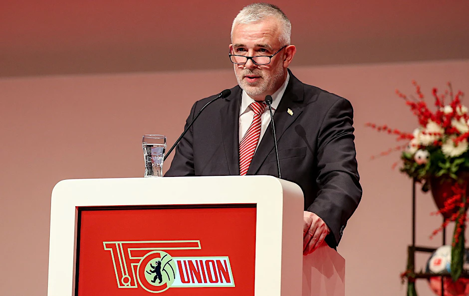 Präsident Dirk Zingler steht an einem Rednerpult.  