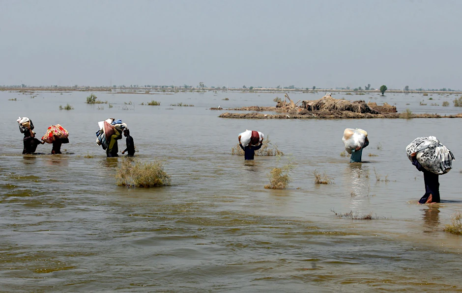 Opfer der schweren Überschwemmungen durch Monsunregen tragen in der Provinz Sindh Hilfsgüter durch das Hochwasser.  