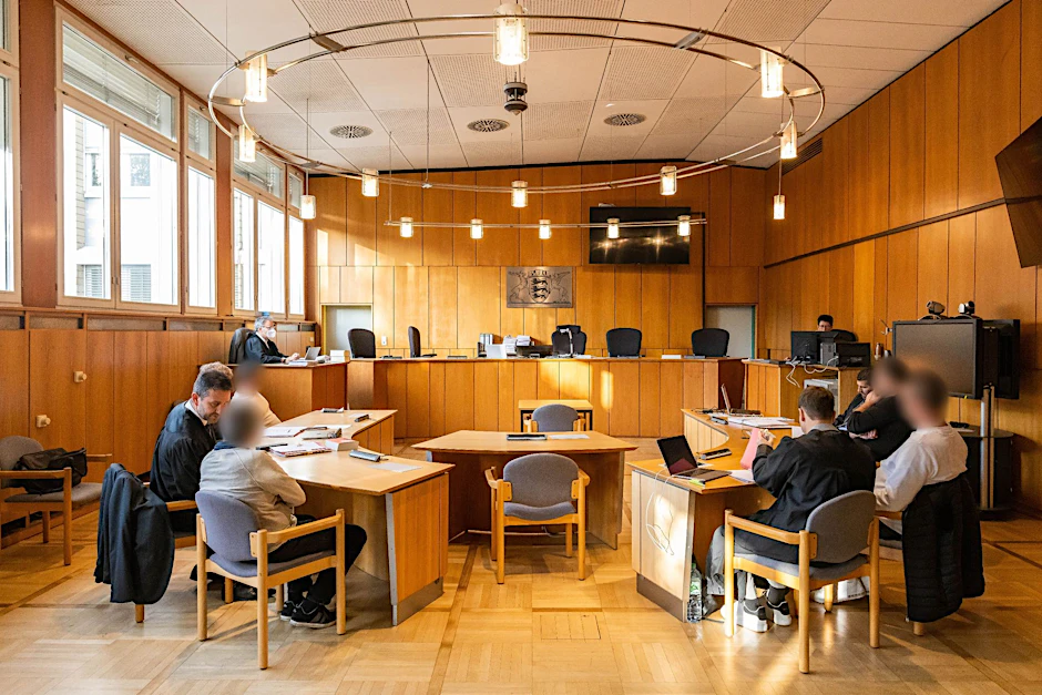 Vier Angeklagte sitzen mit ihren Verteidigern im Vorfeld der Verhandlung in einem Saal des Landgerichts Offenburg.   - Nutzung nur nach schriftlicher Vereinbarung mit der dpa