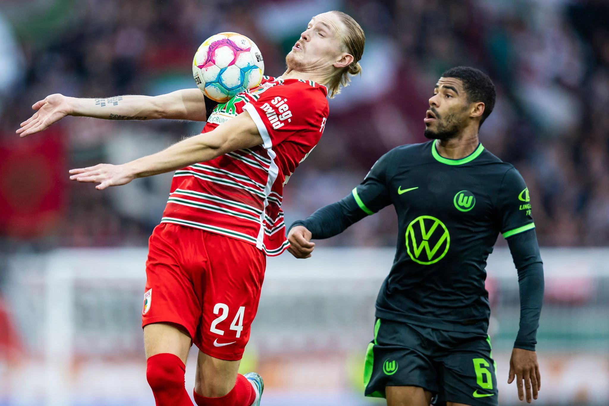 Augsburgs Fredrik Jensen (l) kommt vor dem Wolfsburger Paulo Otavio an den Ball.   - Nutzung nur nach schriftlicher Vereinbarung mit der dpa