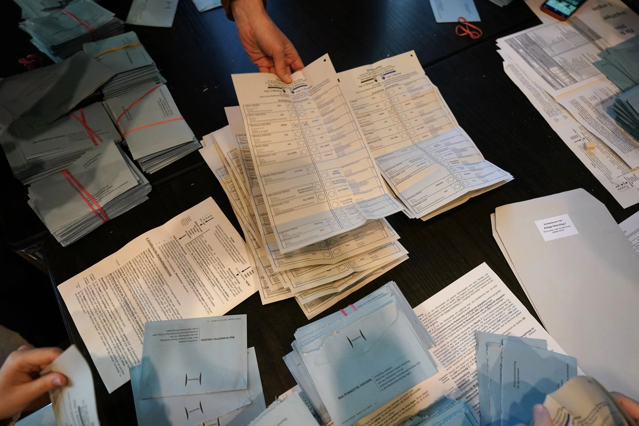 Wahlhelfer sortieren bei der Stimmenauszählung die Wahlzettel.  