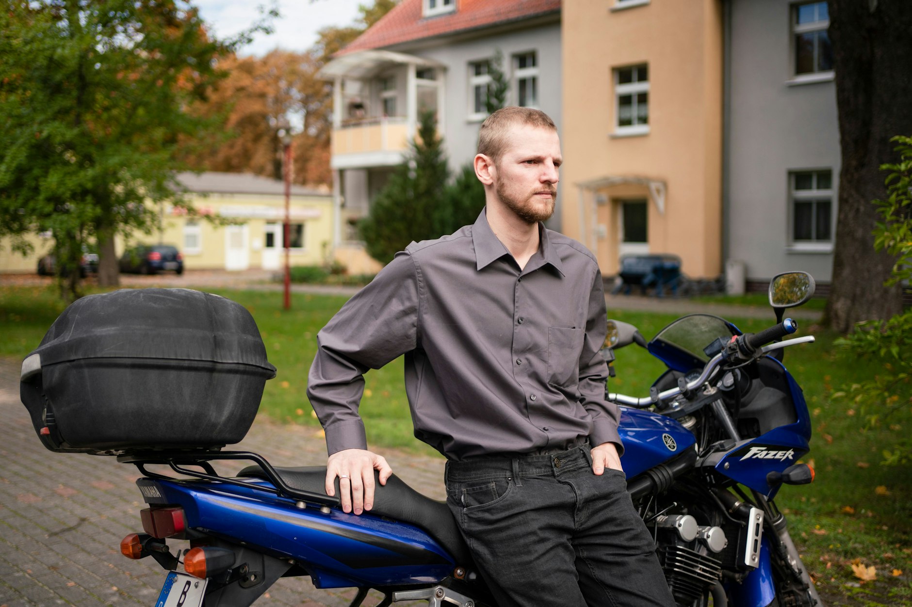 Dustin S. vor seinem Haus. Ab und an fährt er mit dem Motorrad zur Arbeit.