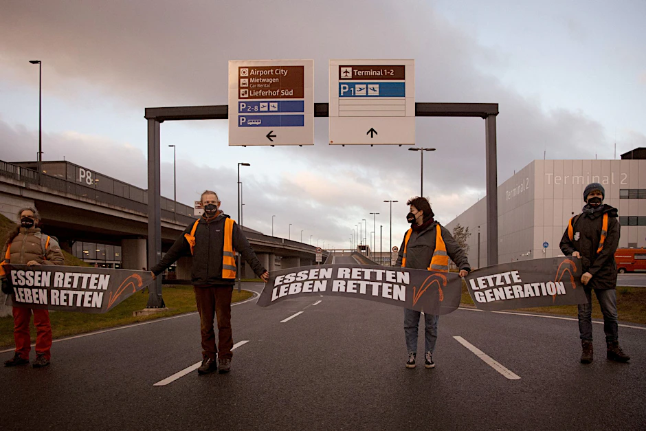 Klimaschutz-Aktivisten blockieren eine Zufahrt zum BER (Archivbild).