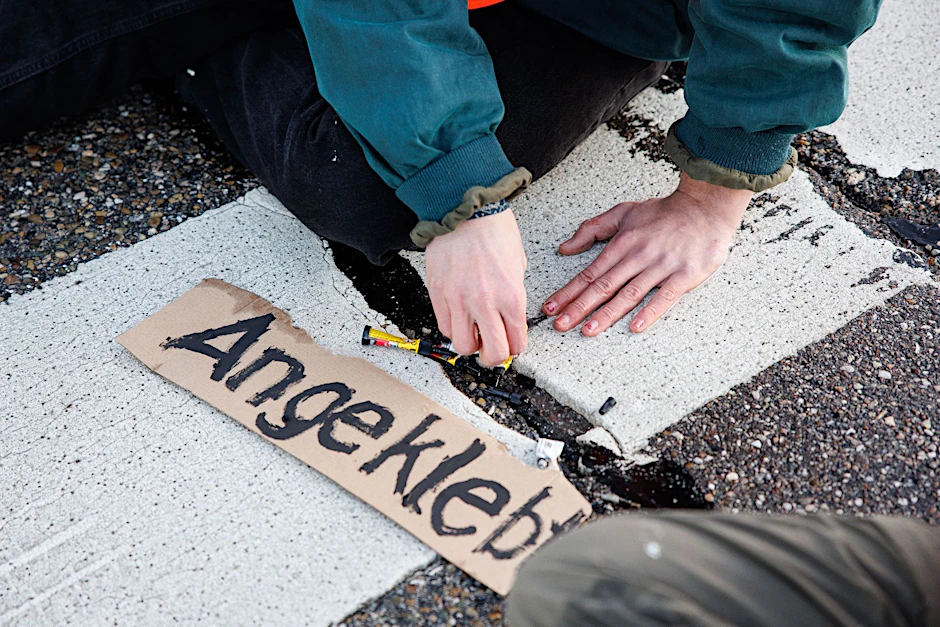 ARCHIV - Ein Aktivist der Gruppe «Die letzte Generation» klebt seine Hand auf der Straße fest.  