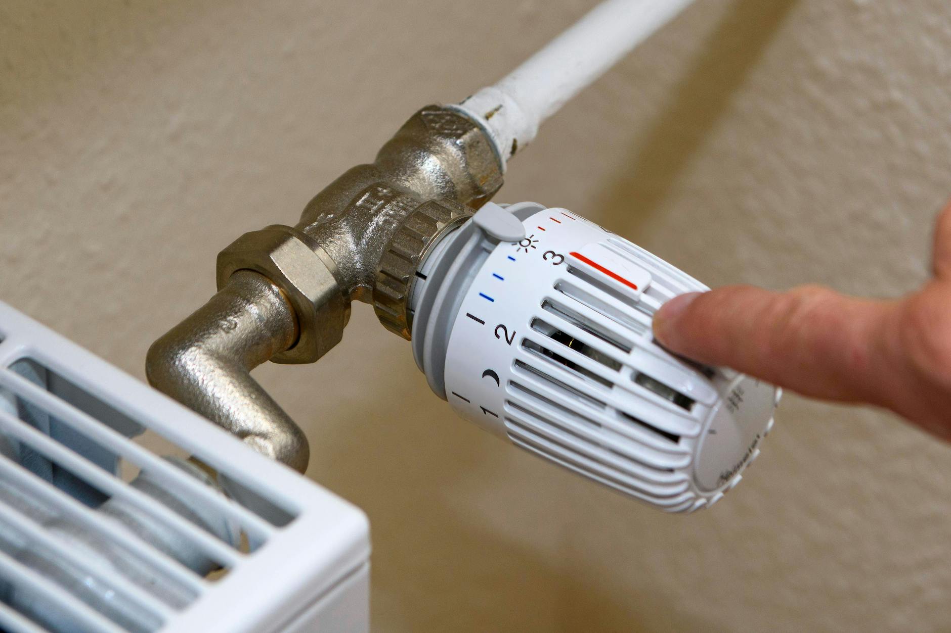 Ein Mann zeigt auf den kleinen Plastikstift auf dem Thermostat.