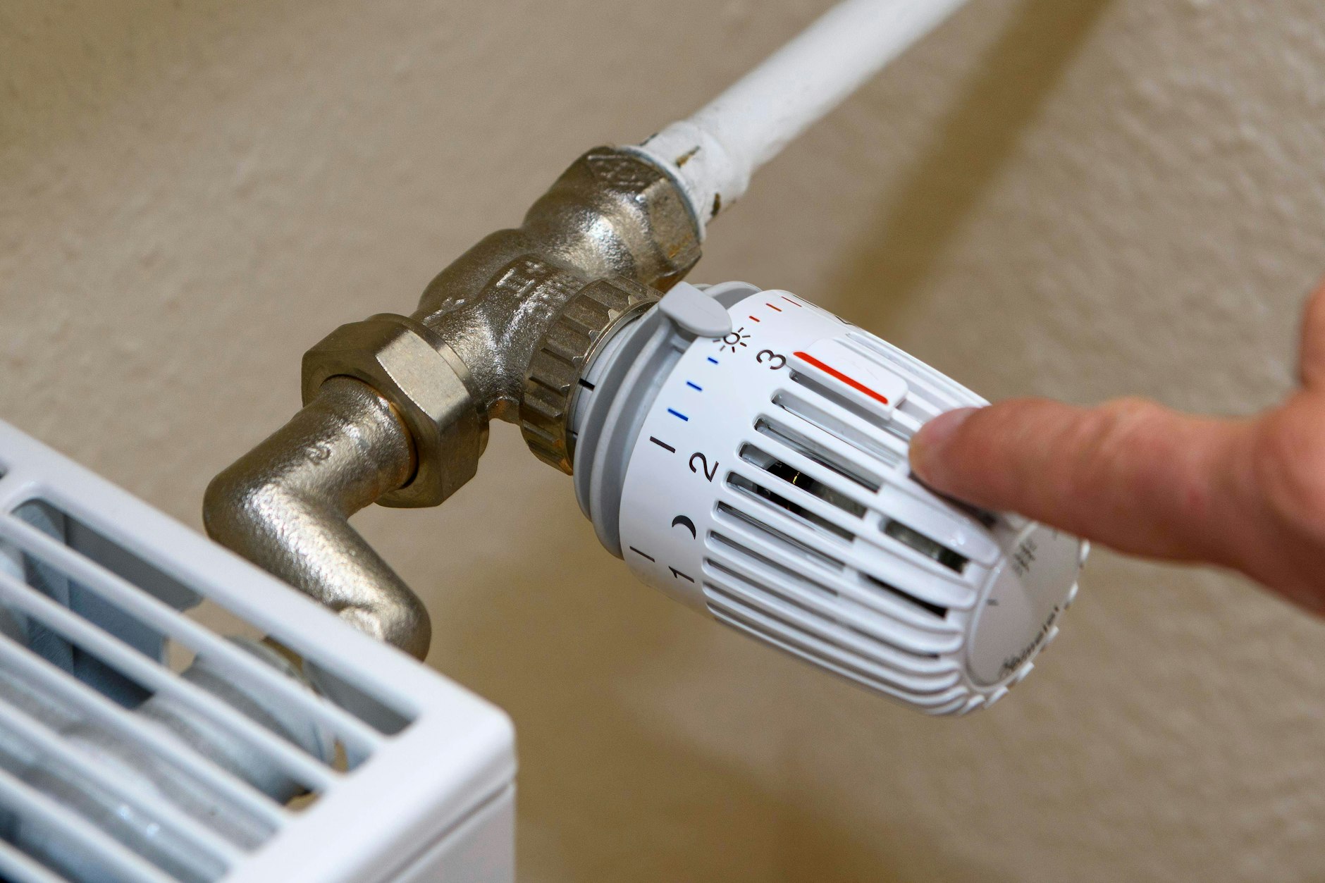 Ein Mann zeigt auf den kleinen Plastikstift auf dem Thermostat.