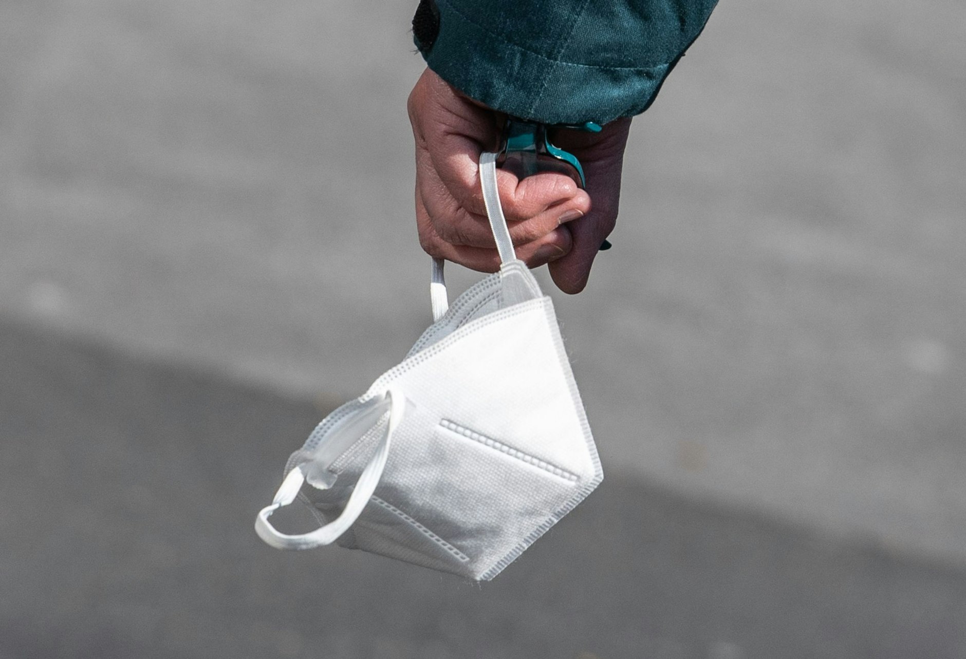 Ein Passant trägt eine FFP2-Maske in der Hand.  