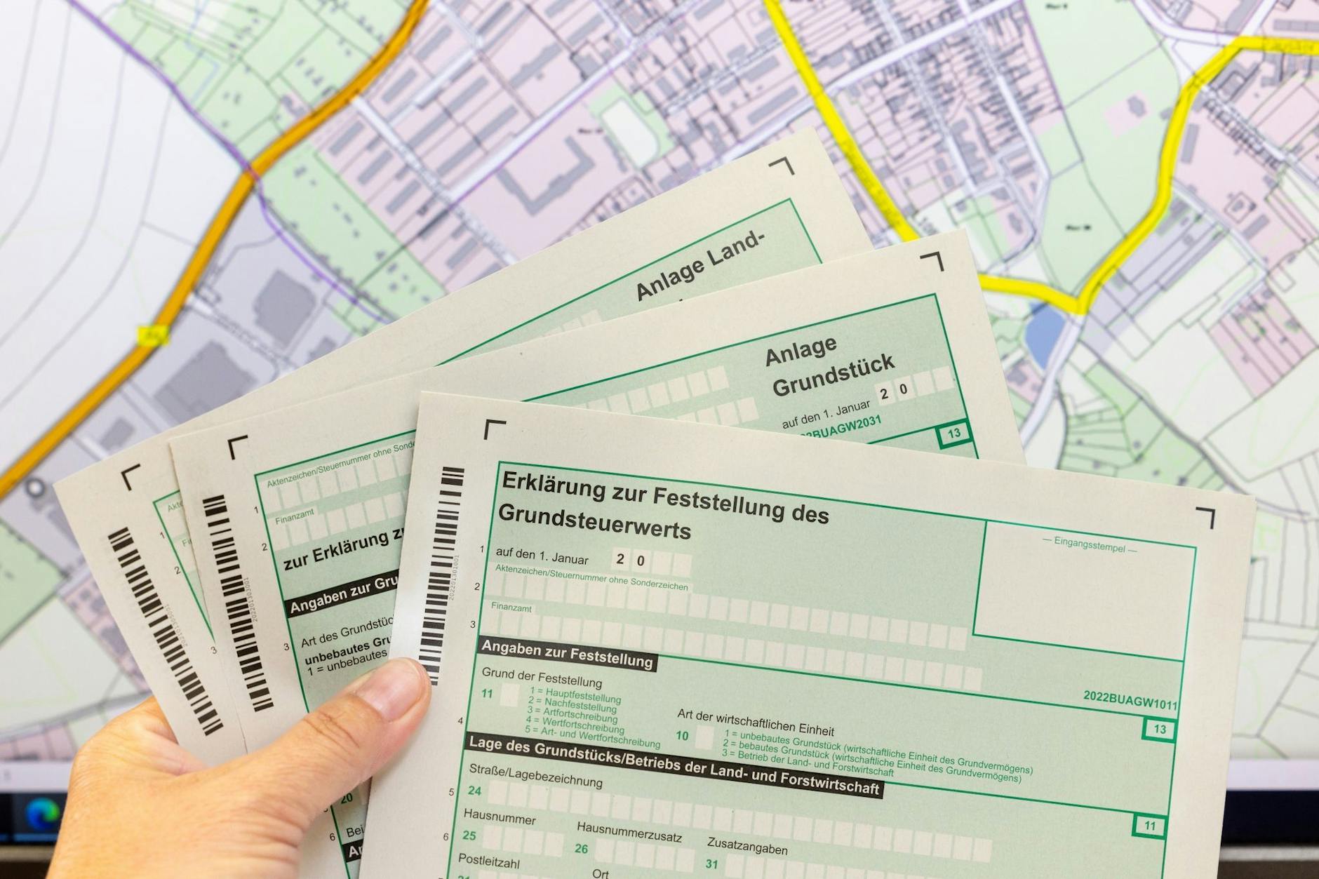 Eine Finanbeamtin hält Formulare zur Grundsteuererklärung in der Hand. 