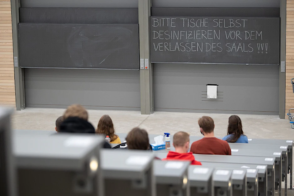 ARCHIV - Studierende mit Mund- und Nasenmaske sitzen in einem Hörsaal.  