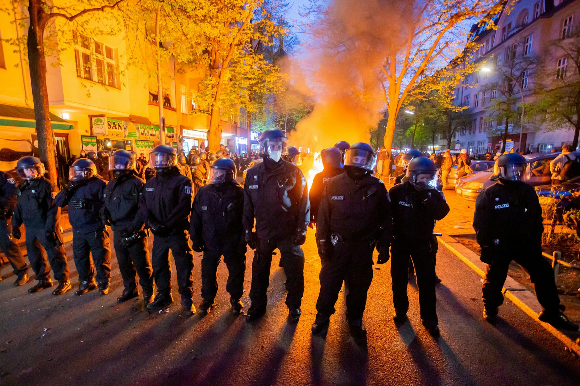 Polizisten stehen am 1. Mai 2021 vor einem Feuer auf der Straße am Rande der Demonstration linker und linksradikaler Gruppen.