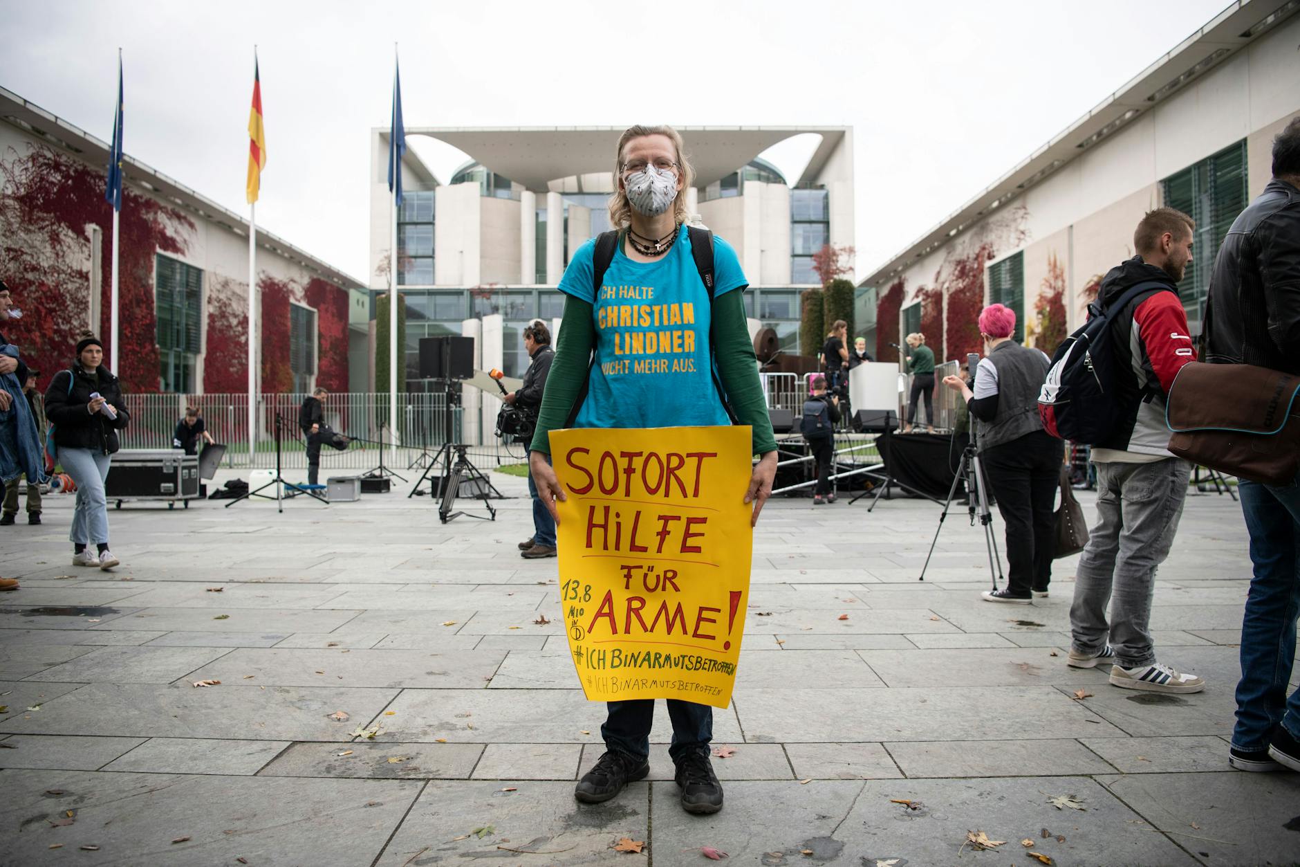 Eine Teilnehmerin der Kundgebung der Initiative #ichbinarmutsbetroffen steht mit einem Plakat mit der Aufschrift „Sofort Hilfe für Arme“ am Bundeskanzleramt. 