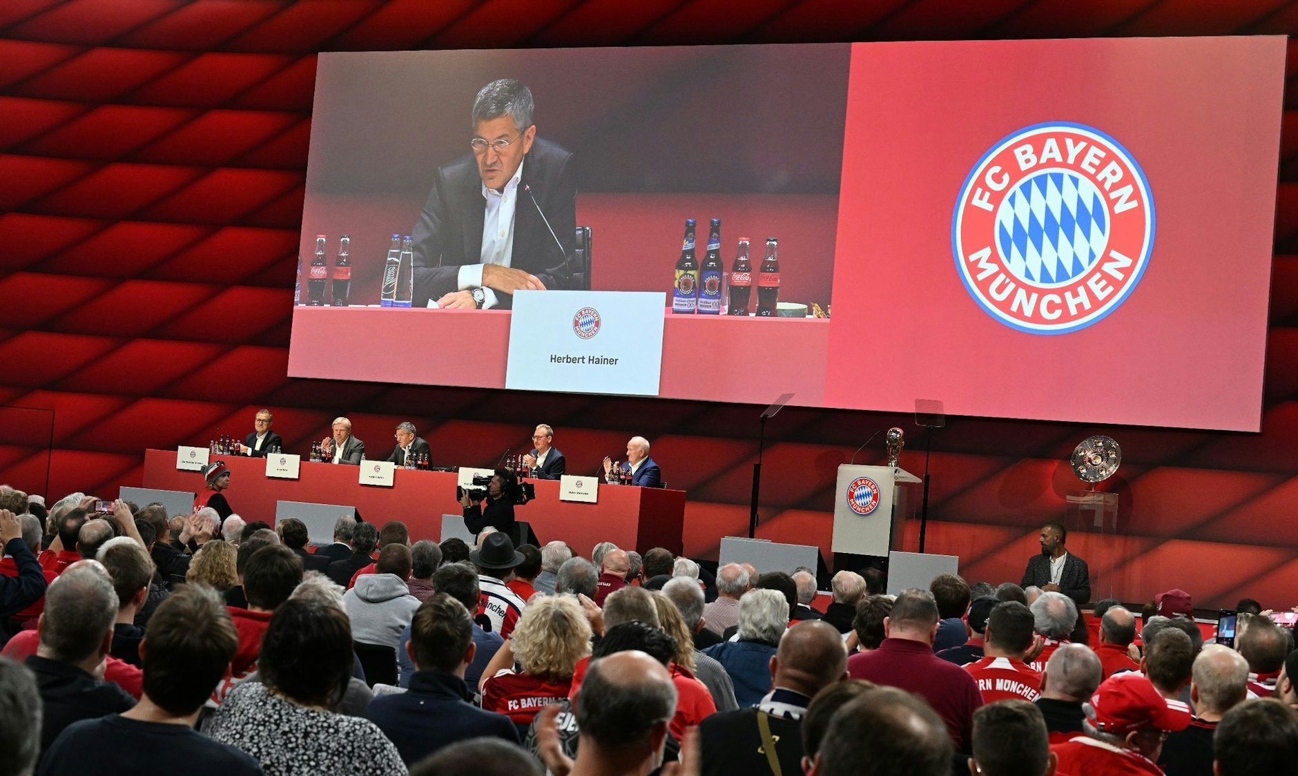 Mitglieder verfolgen die Jahreshauptversammlung, auf der Leinwand Bayern-Präsident Herbert Hainer.   - Nutzung nur nach schriftlicher Vereinbarung mit der dpa