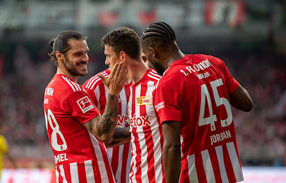 Union Berlins Christopher Trimmel (l) und Jordan Siebatcheu (r) gratulieren Janik Haberer zum 2:0.  
