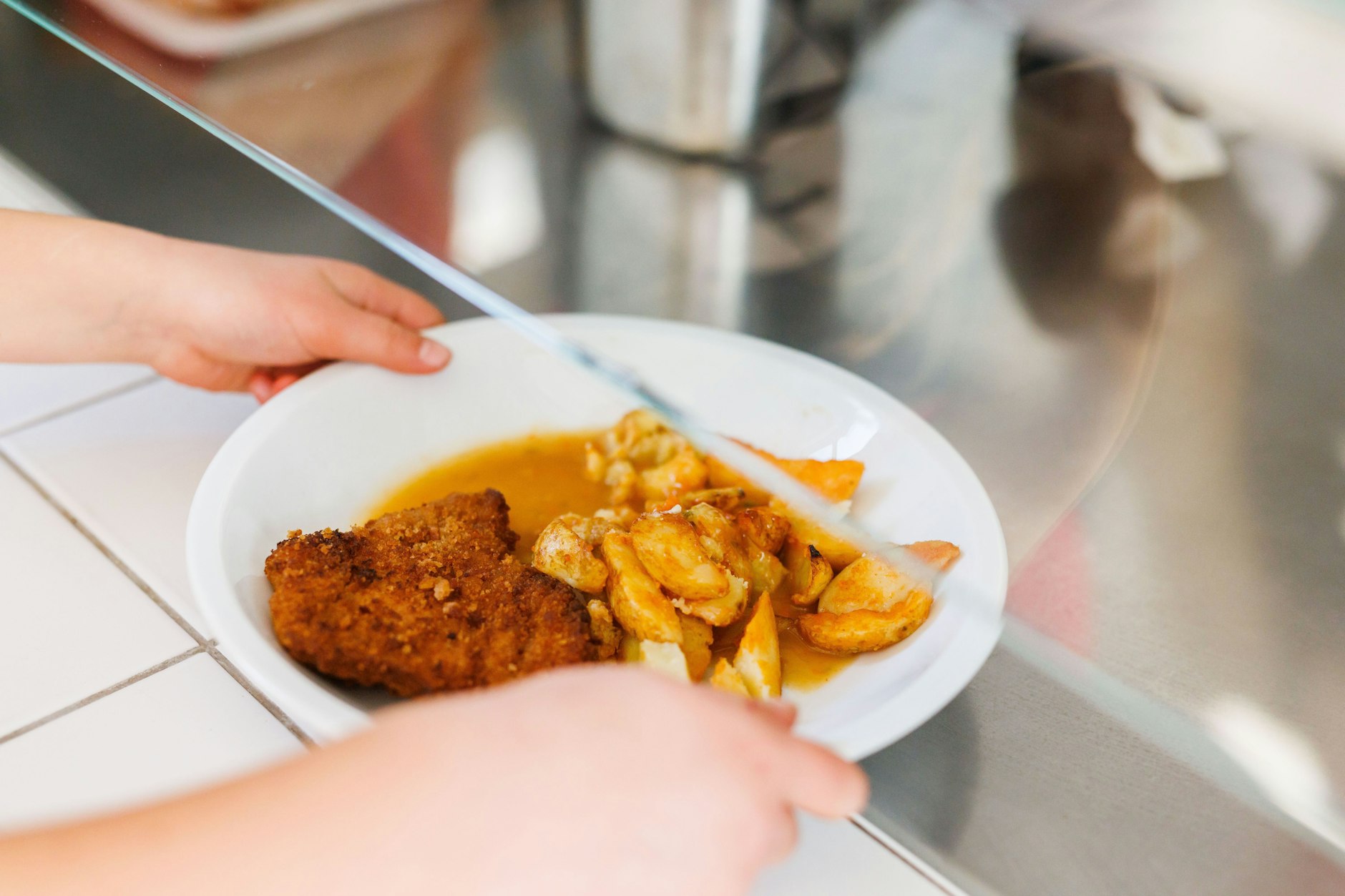 Szenen der Vergangenheit? Eine Freiburger Grundschülerin nimmt einen Teller mit Schnitzel, Kartoffeln und Sauce vom Tresen der Essensausgabe einer Schulmensa.