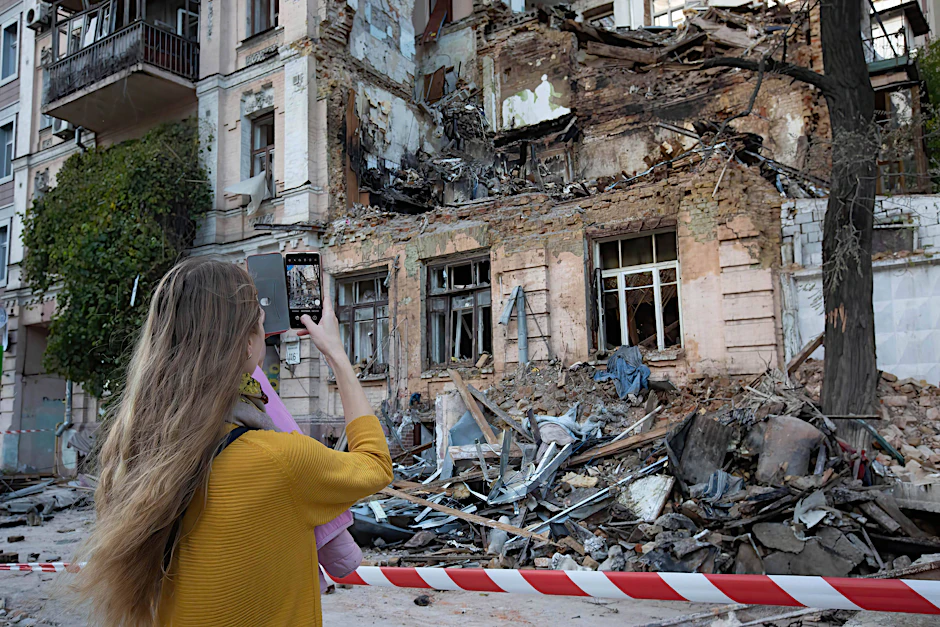 Eine junge Frau fotografiert ein Wohnhaus im Zentrum von Kiew, das durch einen russischen Drohnenangriff zerstört wurde.