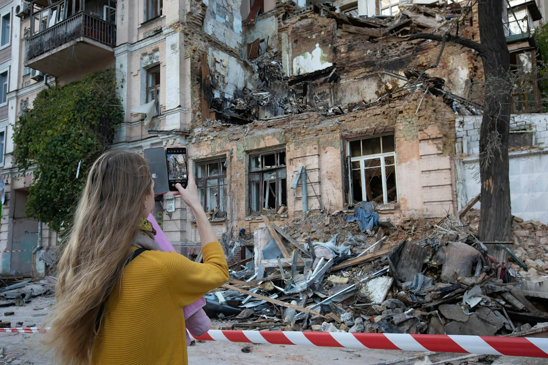 Eine junge Frau fotografiert ein Wohnhaus im Zentrum von Kiew, das durch einen russischen Drohnenangriff zerstört wurde.
